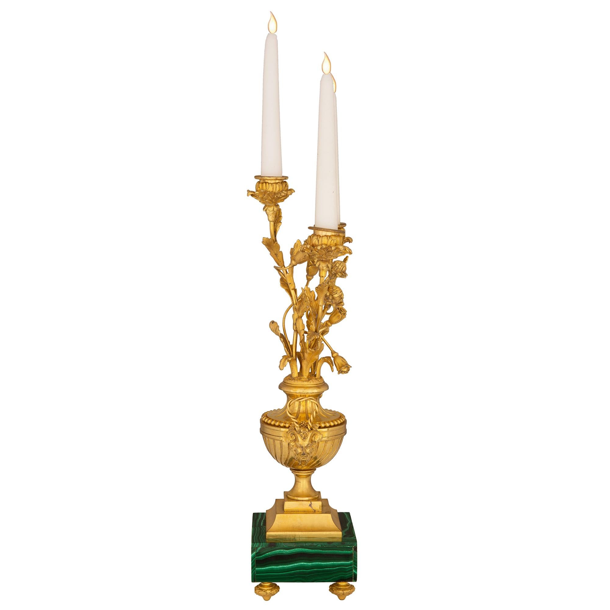 Excepcional pareja de candelabros de tres brazos de ormolina y malaquita franceses de mediados del siglo XIX, de estilo Luis XVI. Cada candelabro se eleva sobre una base cuadrada de malaquita con finas patas de ormolu en forma de topie. Los soportes