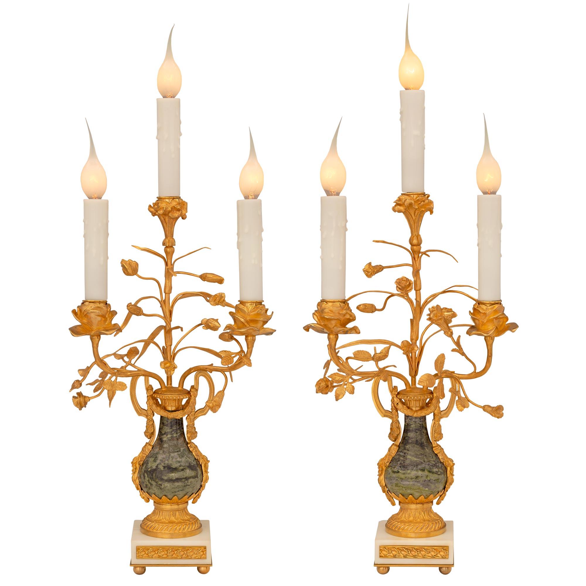 A striking and high quality pair of French 19th century Louis XVI st. ormolu and marble candelabra lamps. Each three arm lamp is raised by an elegant square white Carrara marble base with fine ormolu ball feet and a fitted foliate ormolu plaque at