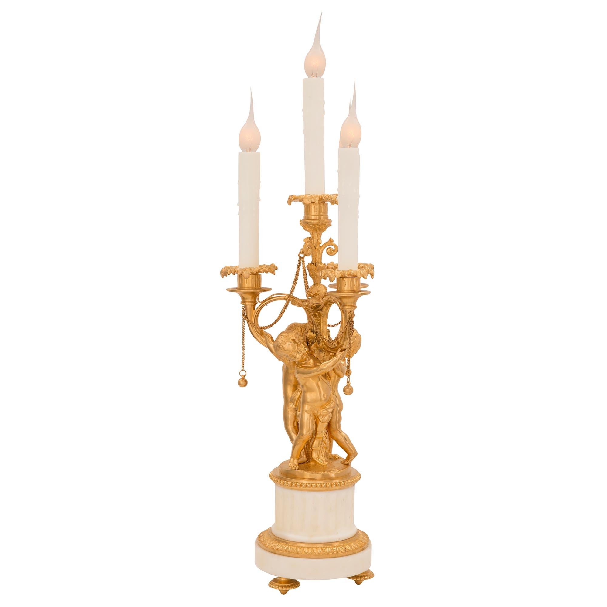 A most elegant pair of French 19th century Louis XVI st. Belle Époque period ormolu and White Carrara marble candelabra lamps. Each four arm lamp is raised by fine ormolu topie shaped feet below the circular white Carrara marble base decorated with