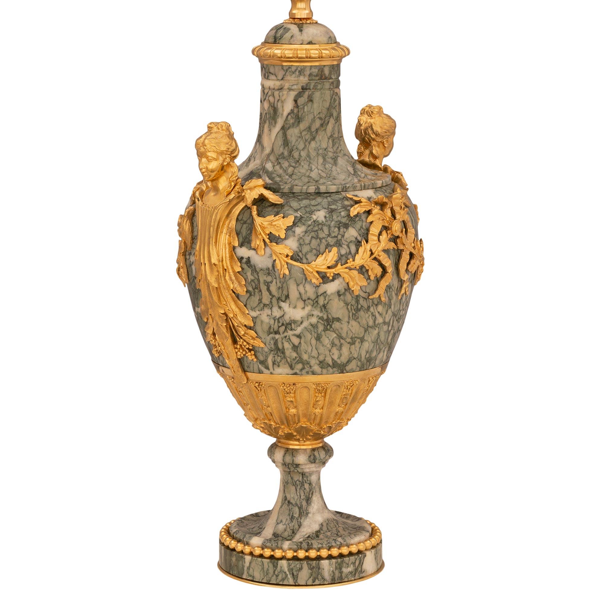 A striking and extremely elegant true pair of French 19th century Louis XVI st. ormolu and Vert Campan marble lamps attributed to Henry Dasson. Each lamp is raised by a circular base with a fine bottom ormolu fillet and a most decorative wrap around