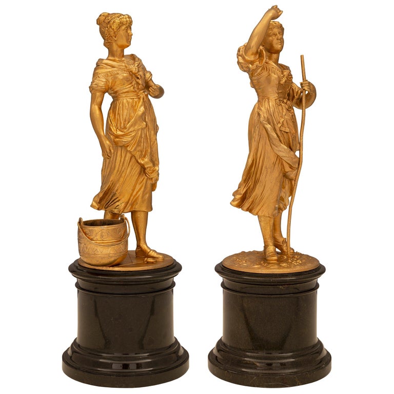 An exceptional true pair of French 19th century Louis XVI st. ormolu and black Belgian marble statues. Each statue is raised by a circular black Belgian marble base with a fine mottled design. The ormolu statues above each display a lovely ground
