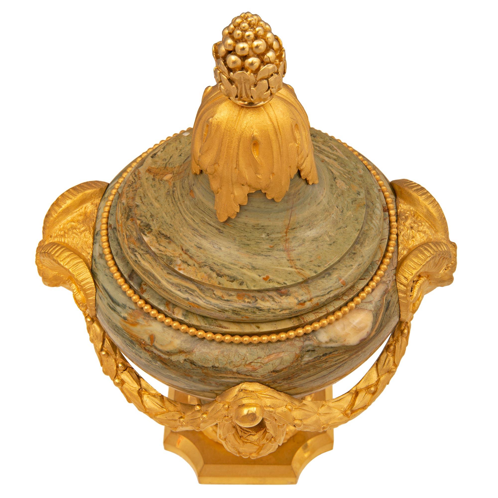 A remarkable and very high quality pair of French 19th century Louis XVI st. Belle Époque period ormolu and Verde marble urns. Each urn is raised by an elegant square ormolu base with concave corners and a fine mottled border. The socle shaped