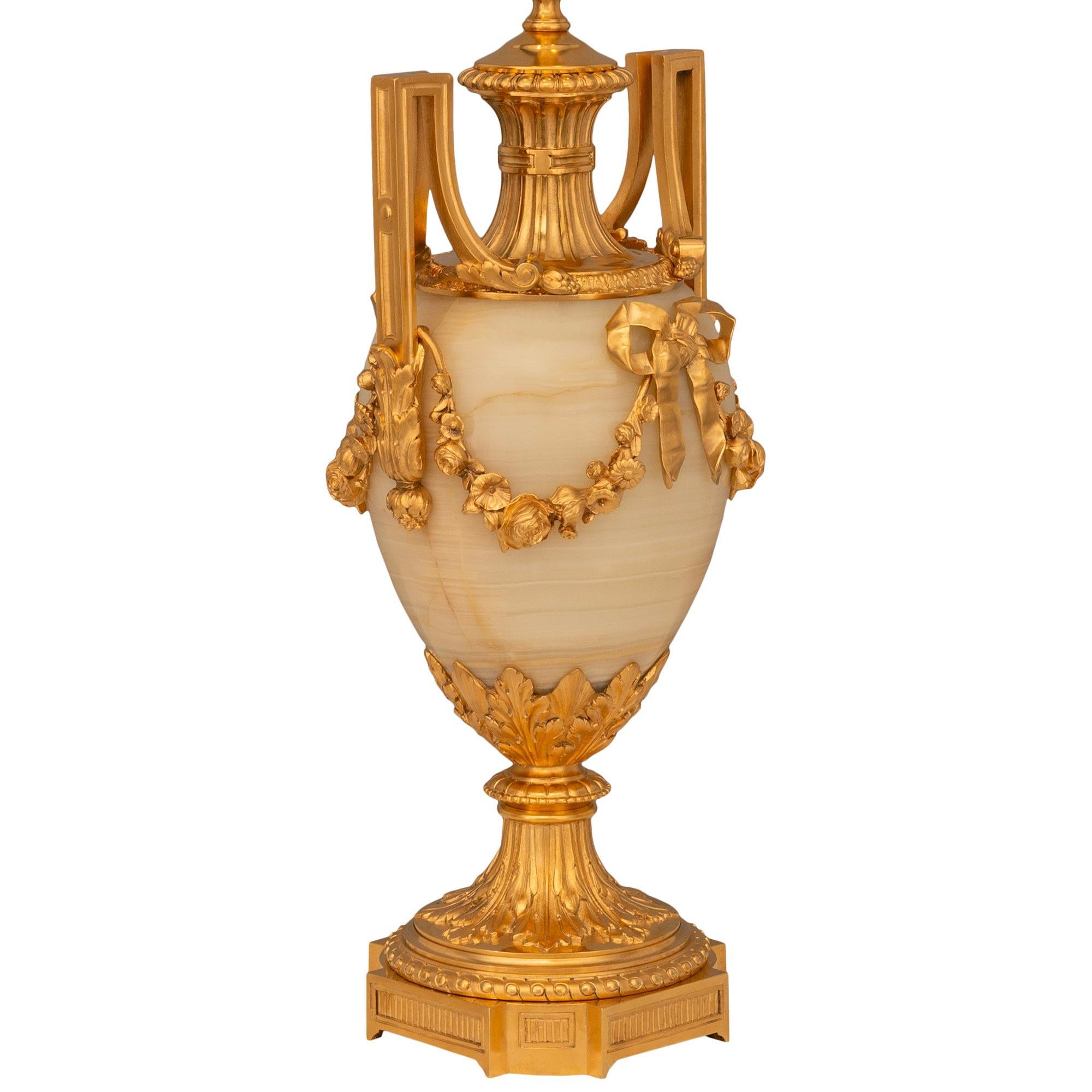 A beautiful and finely decorated pair of French 19th century Louis XVI st. Ormolu and Onyx lamps, signed Henri Picard. This wonderful pair is raised by a square pedestal with recessed corners and reeded panels. The socle above has a beaded and
