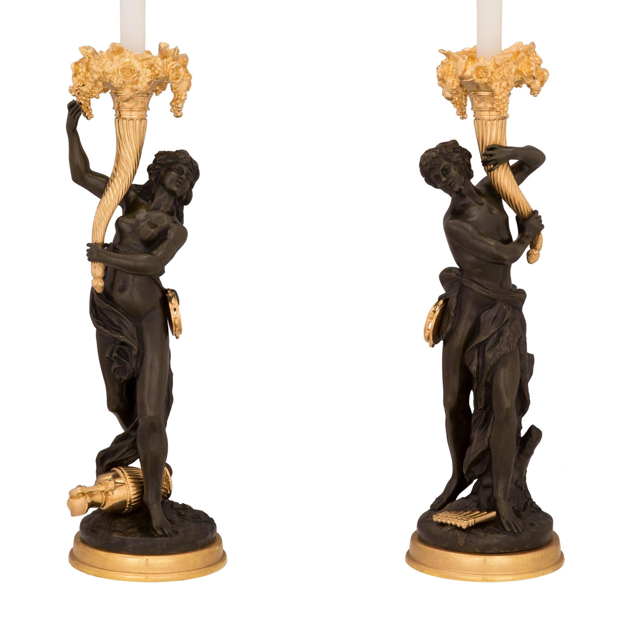 Une belle paire de lampes françaises du 19ème siècle, de style Louis XVI, en bronze doré et patiné, signées Clodion. Chaque lampe est surélevée par une base en bronze doré de qualité, avec un motif en relief merveilleusement exécuté. Le bronze de
