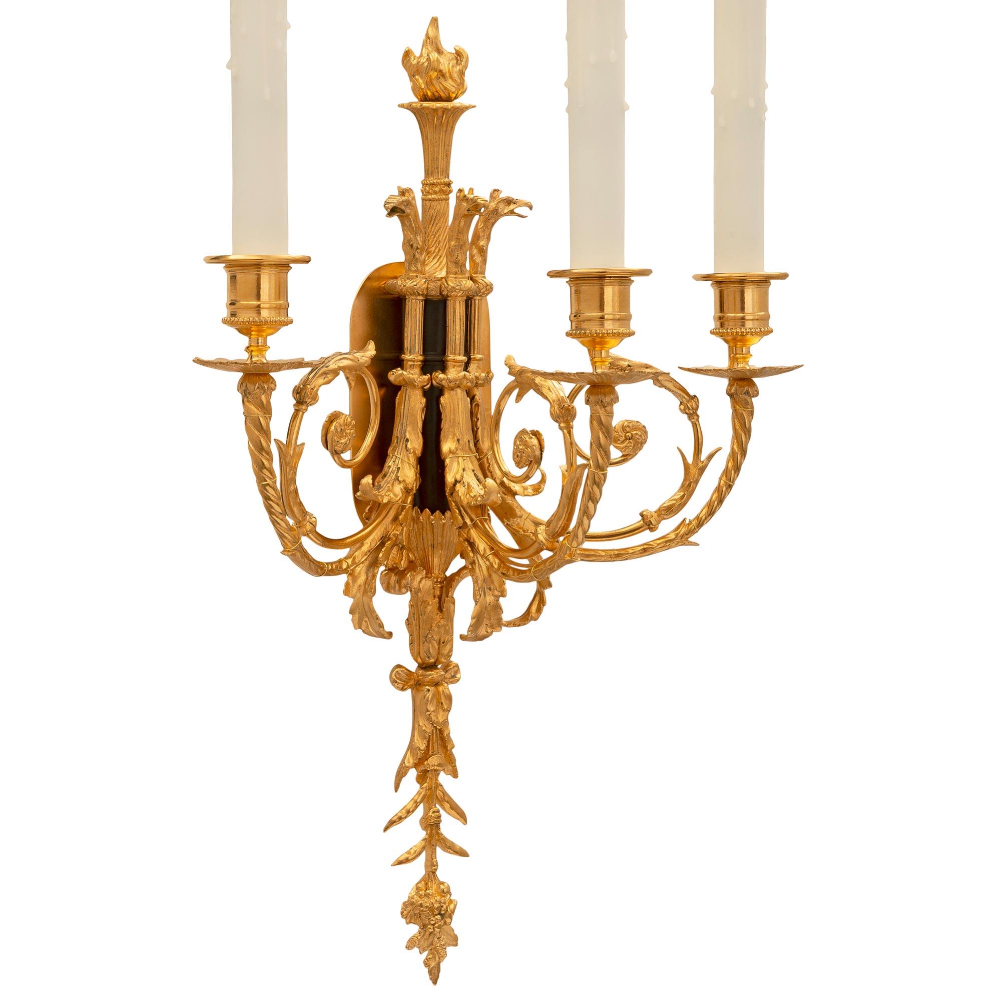 A beautiful and high quality pair of French 19th century Louis XVI st. ormolu and patinated bronze sconces. Each three arm sconce is centered by wonderful tied foliate designs, lovely flowing acanthus leaves, and an exquisite finely detailed finial