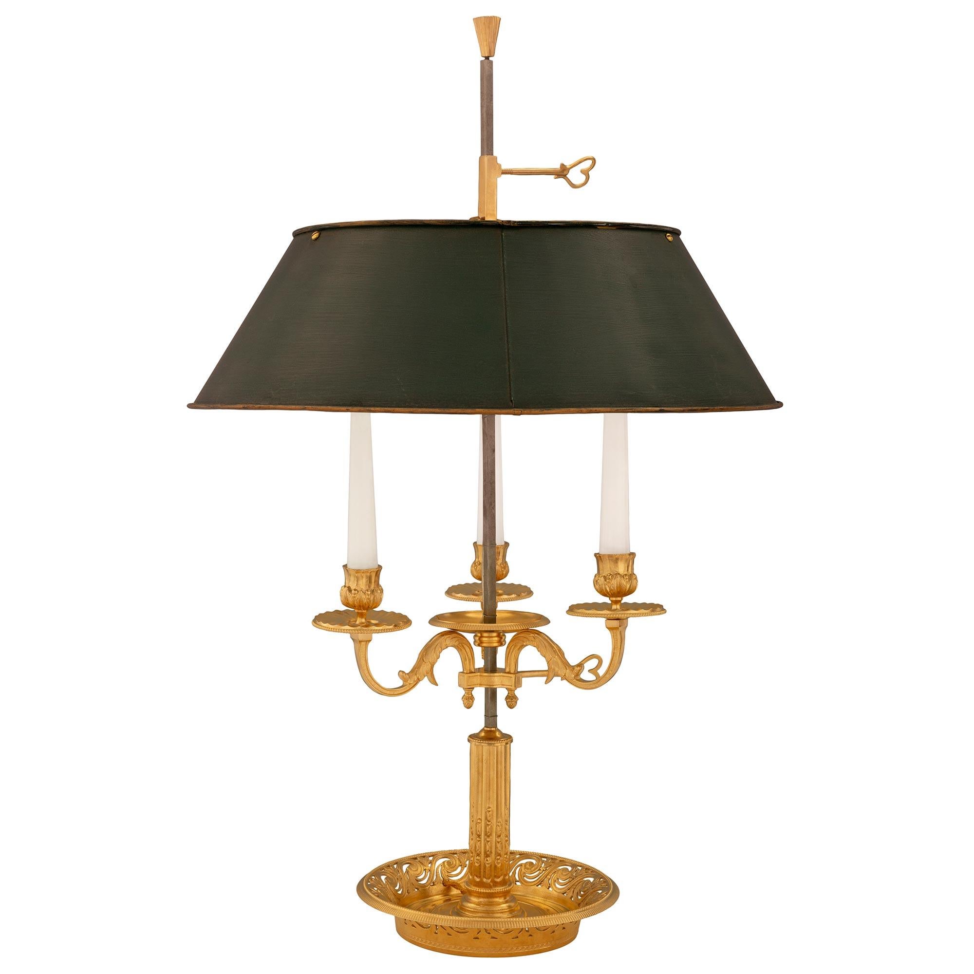 Une paire très élégante de lampes bouillotte de style Louis XVI du 19ème siècle, en bronze doré et en tole. Chaque lampe à trois bras est surélevée par une belle base circulaire percée avec de jolis motifs feuillus imbriqués et des bandes texturées