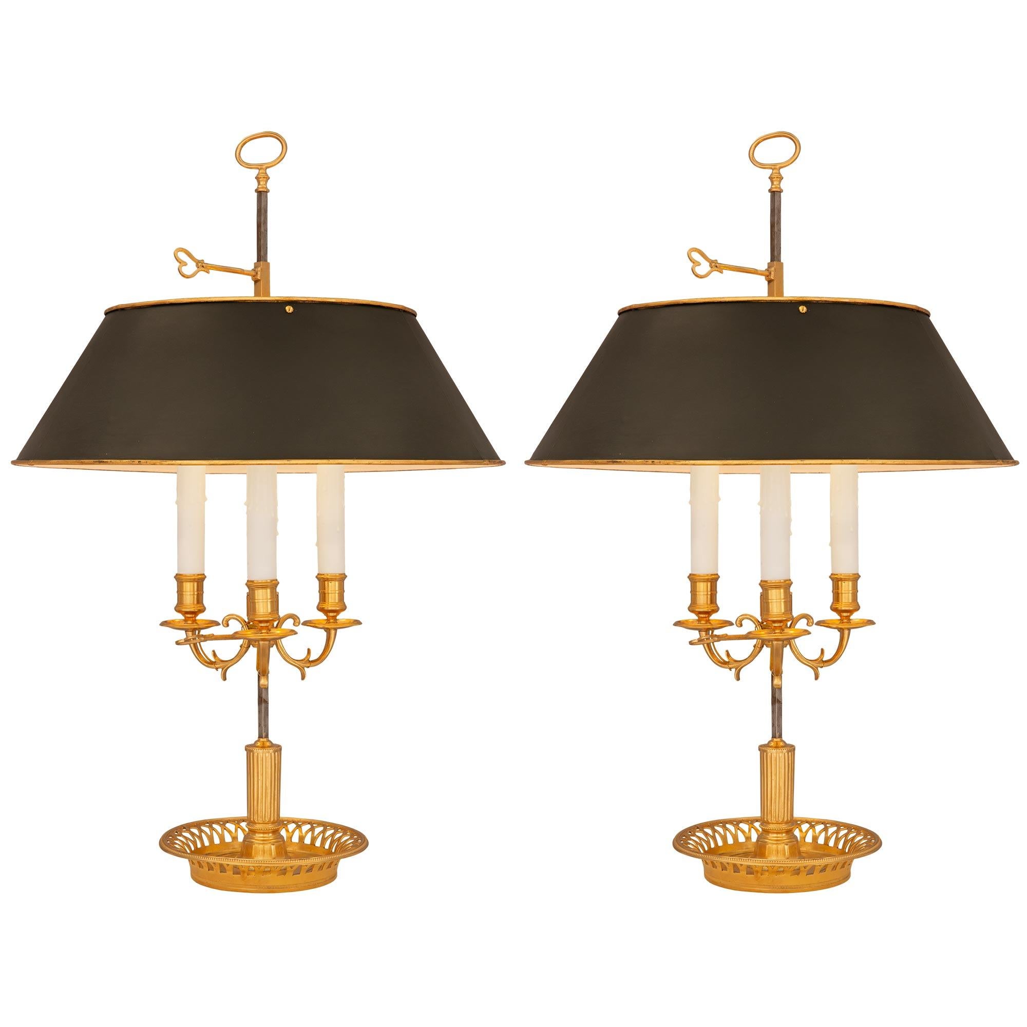 Une paire très élégante de lampes bouillotte en bronze doré de style Louis XVI du 19ème siècle. Chaque lampe est surélevée par une belle coupe circulaire percée de jolis motifs feuillus et d'une bande perlée. Au centre, des supports cannelés mènent