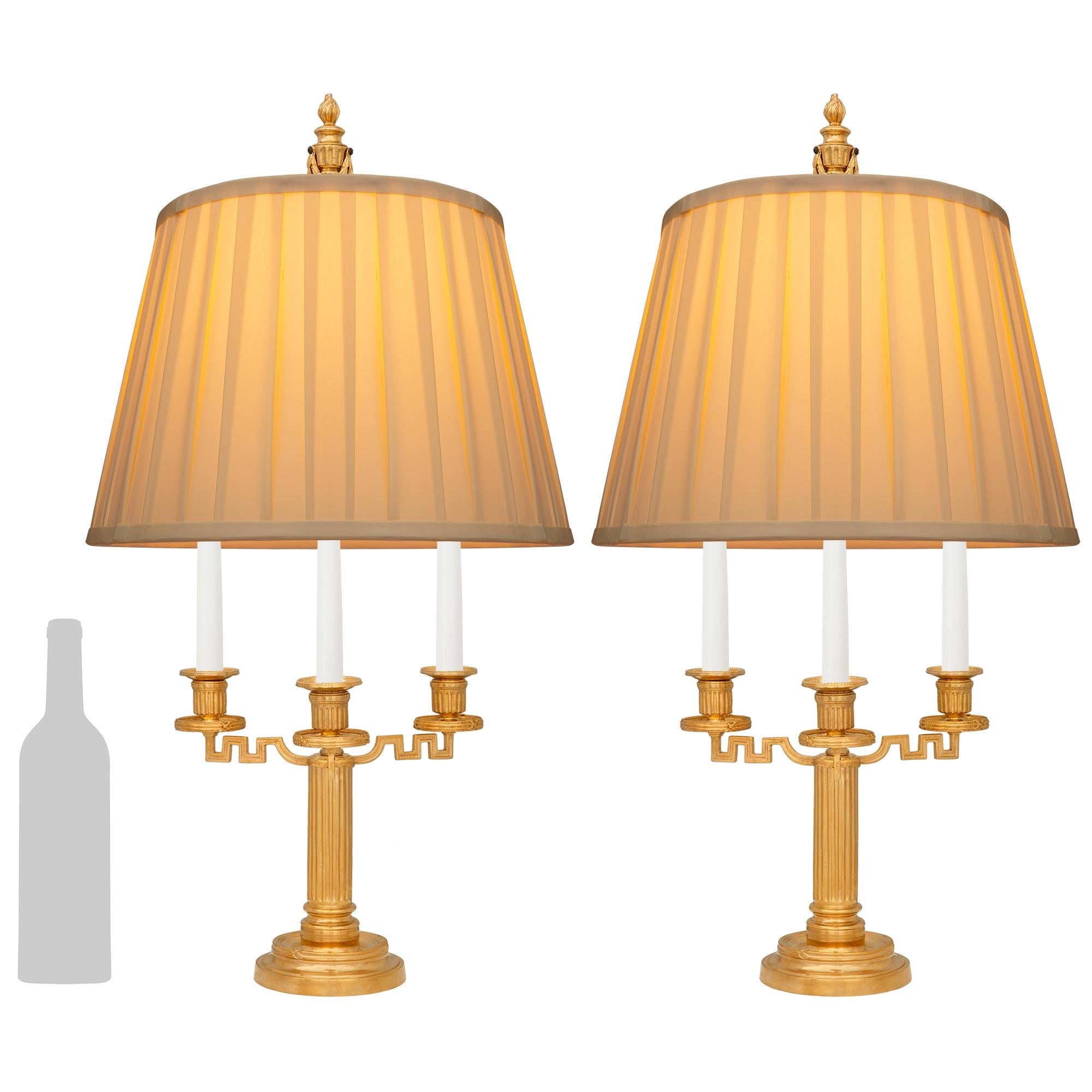 Bonita pareja de lámparas Bouillotte de Ormolu del siglo XIX de estilo Luis XVI francés. Cada maravilloso candelabro montado en una lámpara se eleva sobre unas bases circulares moteadas con diseños de cintas cruzadas. Encima hay una columna