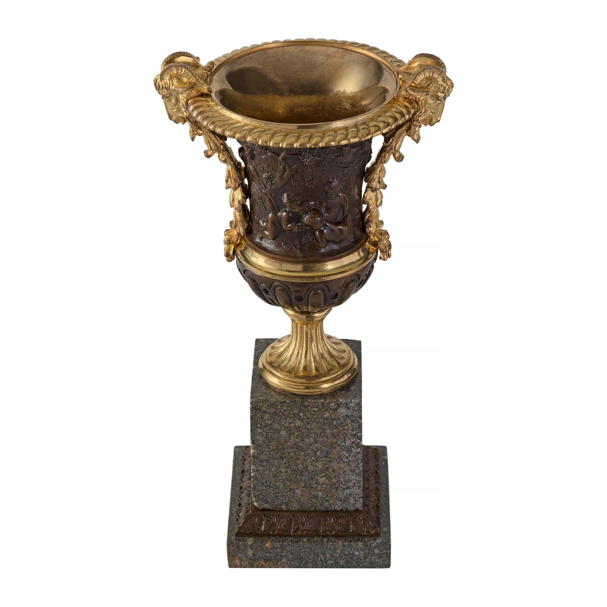 A striking pair of French 19th century Louis XVI st. ormolu, patinated bronze and granite urns. Each urn is raised by a square granite base with a foliate wrap around patinated bronze band. The circular fluted socle pedestal displays a most