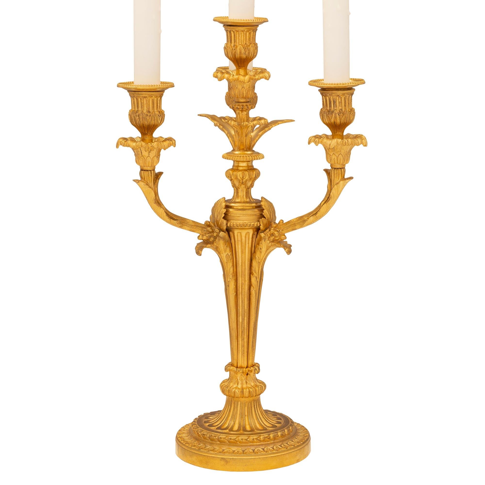 An elegant and high quality pair of French 19th century Louis XVI st. ormolu candelabra lamps. Each four arm lamp is raised by a beautiful mottled circular base with lovely wrap around Coeur de Rai and laurel bands below a striking fluted design in