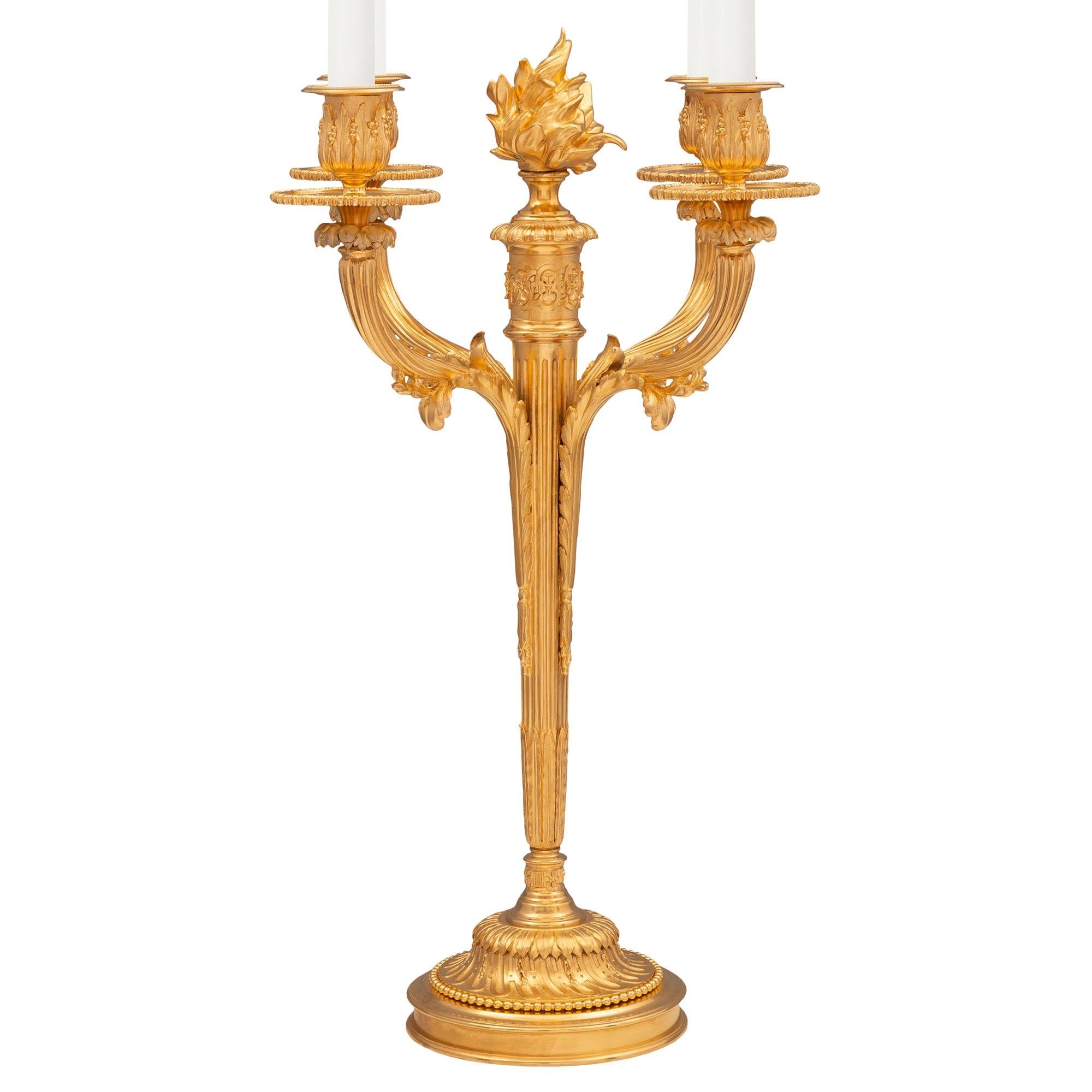 A most elegant pair of French 19th century Louis XVI st. Ormolu candelabras. Each four arm candelabra is raised by a most elegant circular mottled base with a beautiful spiraled acanthus leaf design and a fine wrap around beaded band. The striking