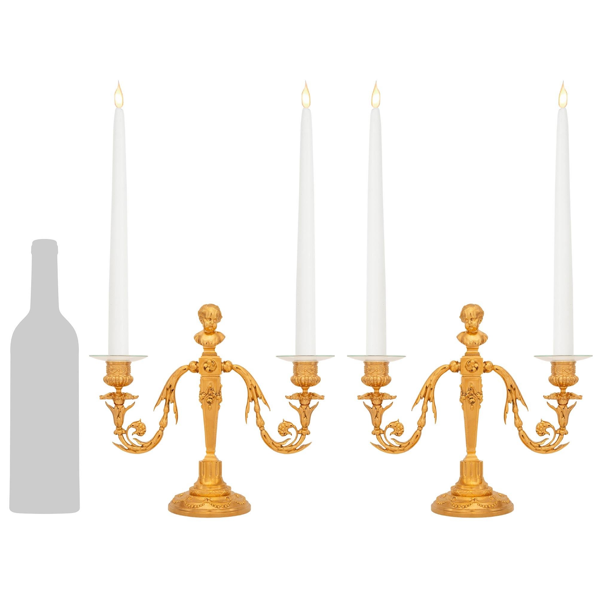 Un'elegante e affascinante coppia di candelabri francesi del XIX secolo in stile Luigi XVI in Ormolu. Ciascun candelabro è supportato da una base circolare in Ormolu screziato, decorata da ghirlande di perline e da una fascia scanalata sotto il