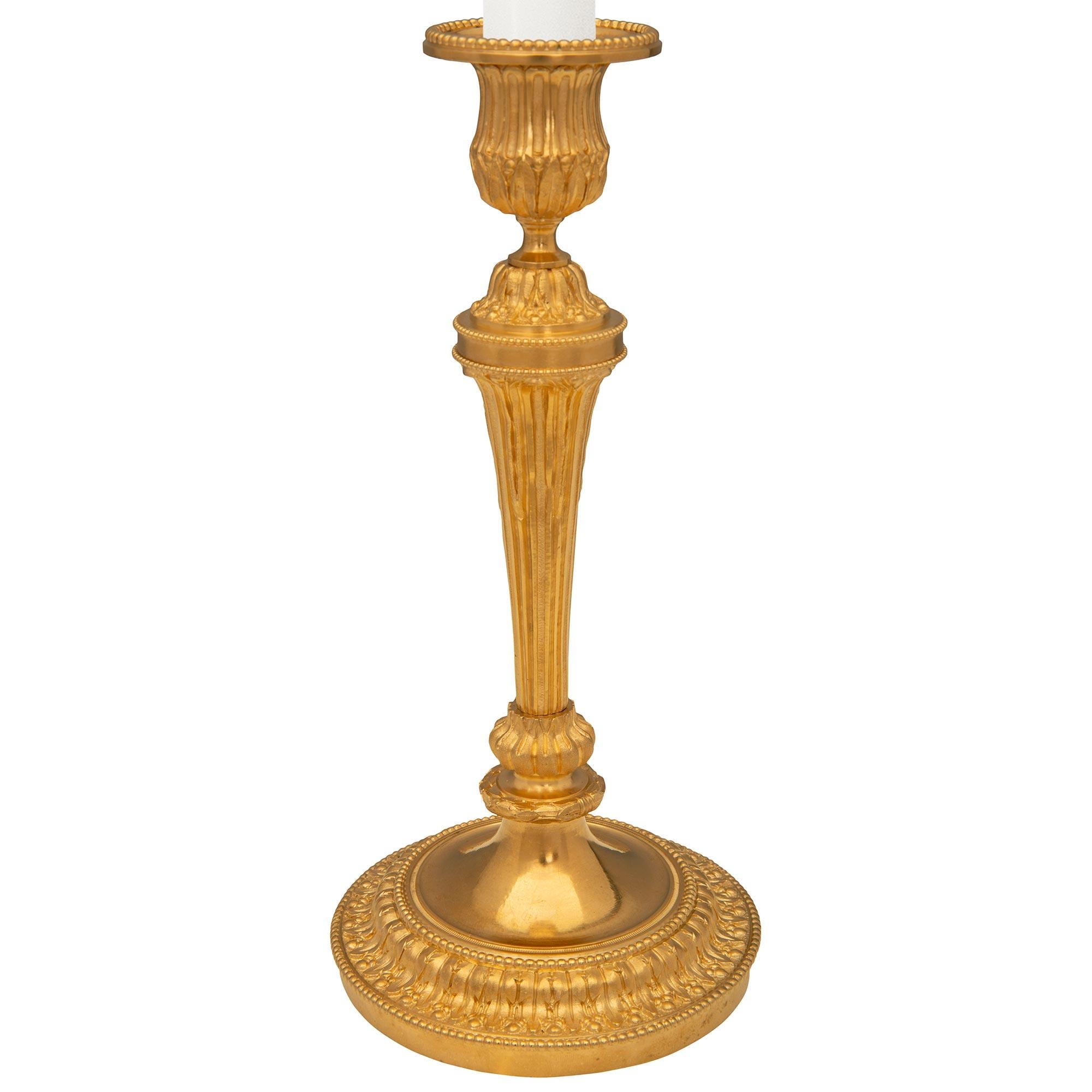 Une paire très élégante de chandeliers en bronze doré de style Louis XVI du XIXe siècle. Chaque chandelier est surélevé par une base circulaire avec une belle bande de feuillage et de perles richement ciselée et mouchetée. Au-dessus des supports de