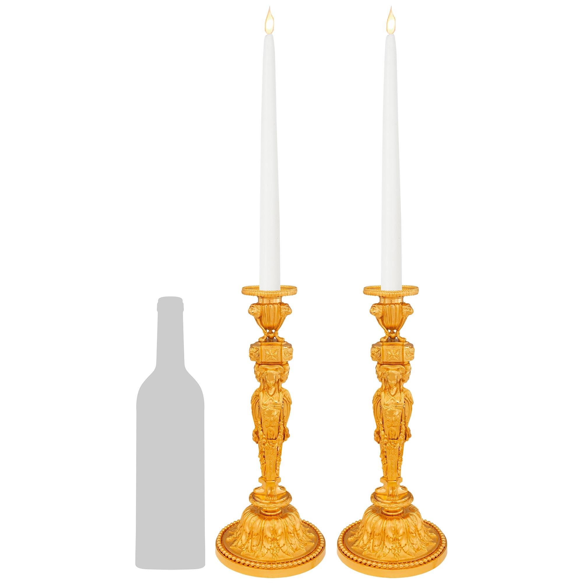 Una splendida e decoratissima coppia di candelabri francesi del XIX secolo in stile Luigi XVI in Ormolu. Ogni splendido candeliere poggia su una base circolare con un raffinato bordo screziato, una fascia di perline e un'ampia fascia decorativa di