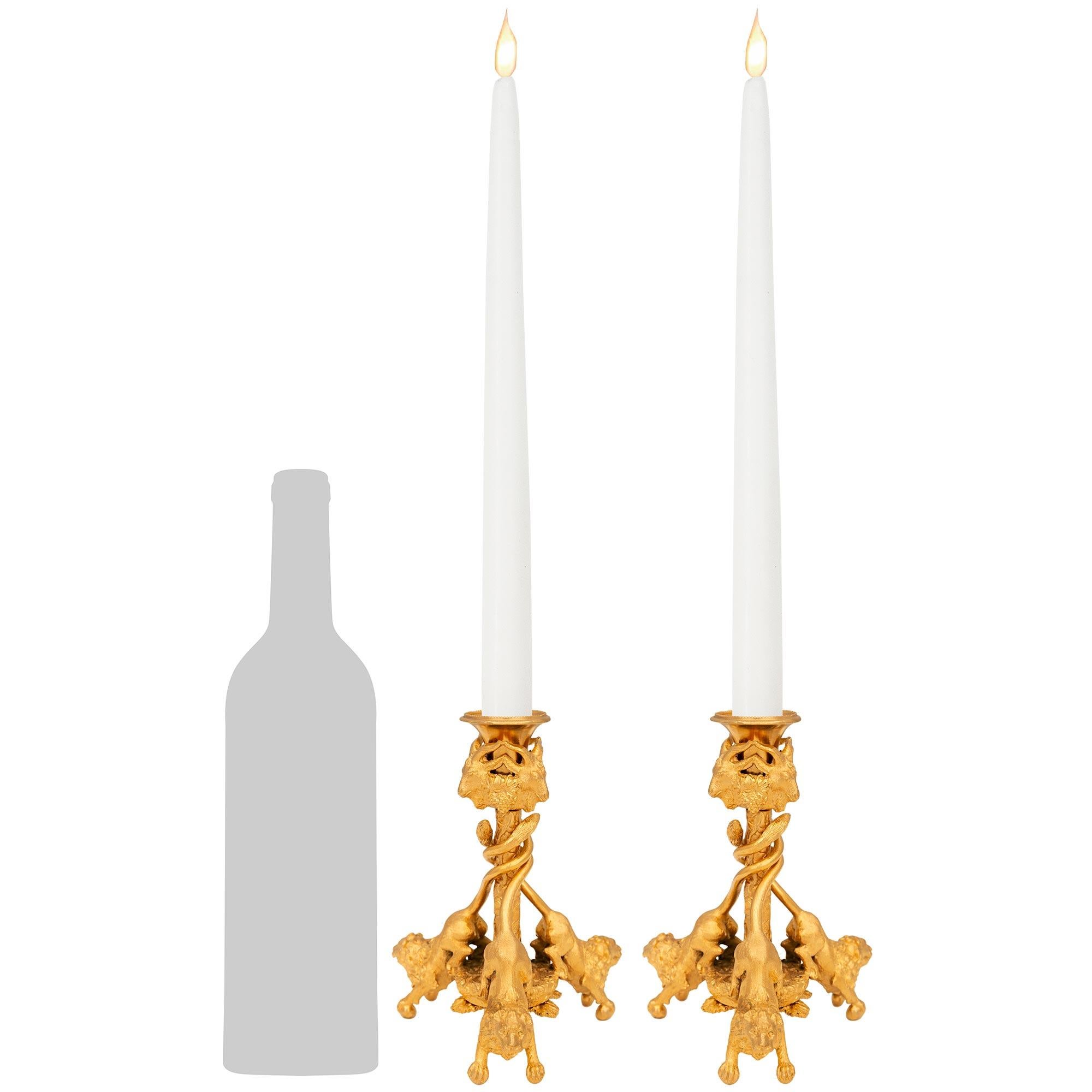 Une merveilleuse et charmante paire de chandeliers en bronze doré de style Louis XVI du 19ème siècle. Chaque beau bougeoir repose sur un trio de lions reposant sur des pieds en boule, dont les queues s'entrelacent autour d'un pilier central décoré