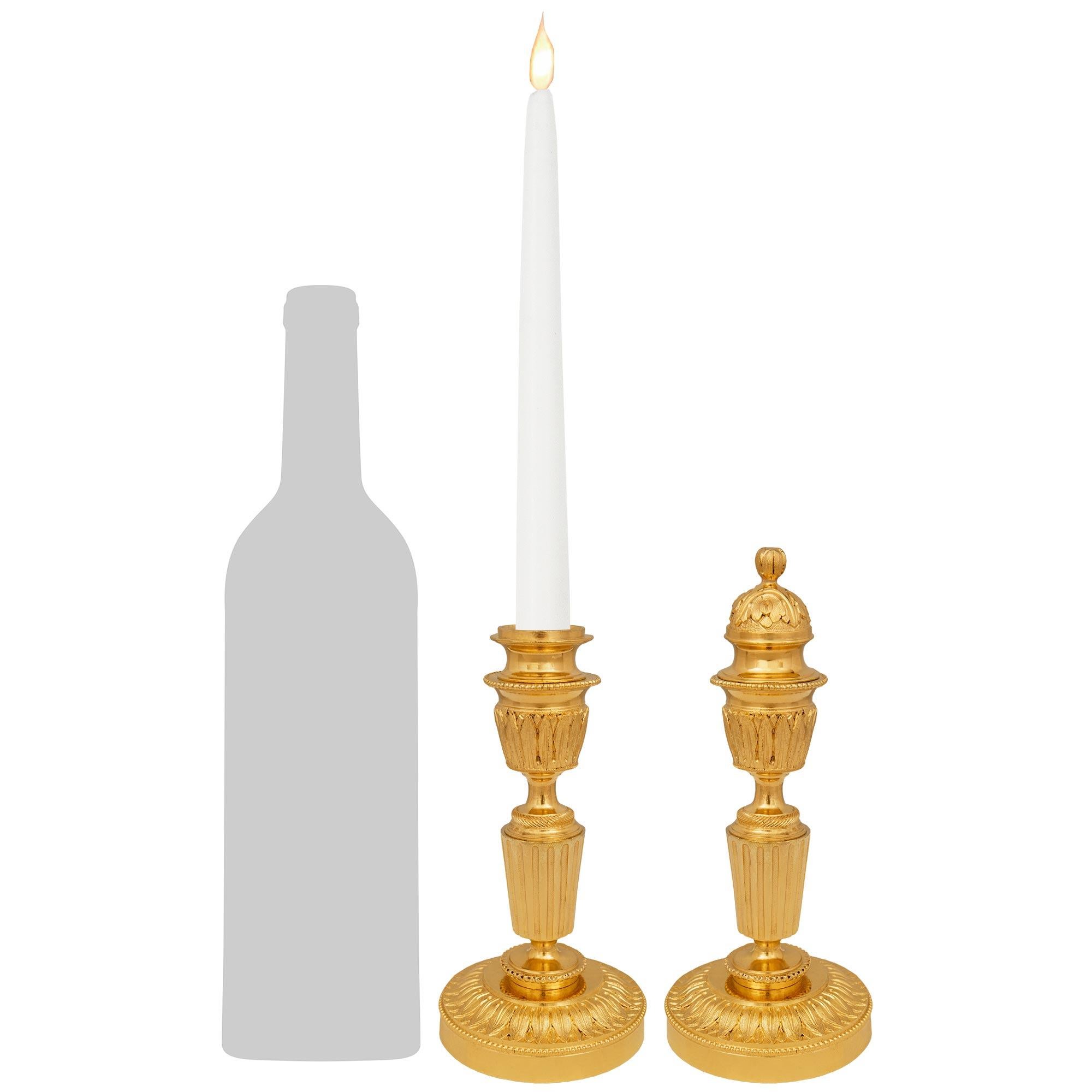 A charming and small scale pair of French 19th century Louis XVI st. Ormolu cassolette candlesticks. Each elegant candlestick is raised by a circular base with a finely chased laurel and outer beaded band. Above is the fluted central fut displaying