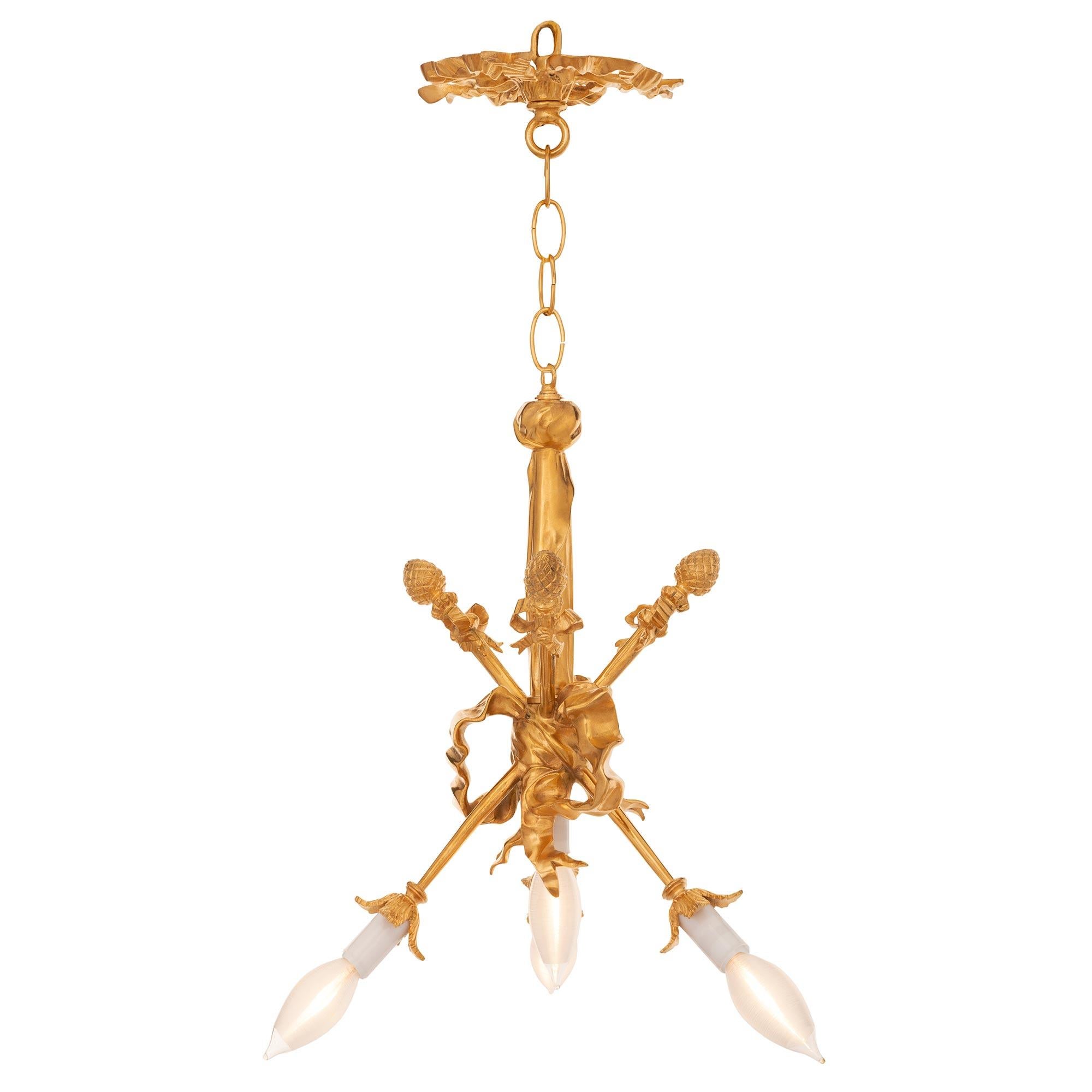 A striking and most unique pair of French 19th century Louis XVI st. ormolu chandeliers. Each three arm, four light chandelier is centered by a single light below a charming wonderfully executed flowing tied ribbon. The ribbon seemingly ties the