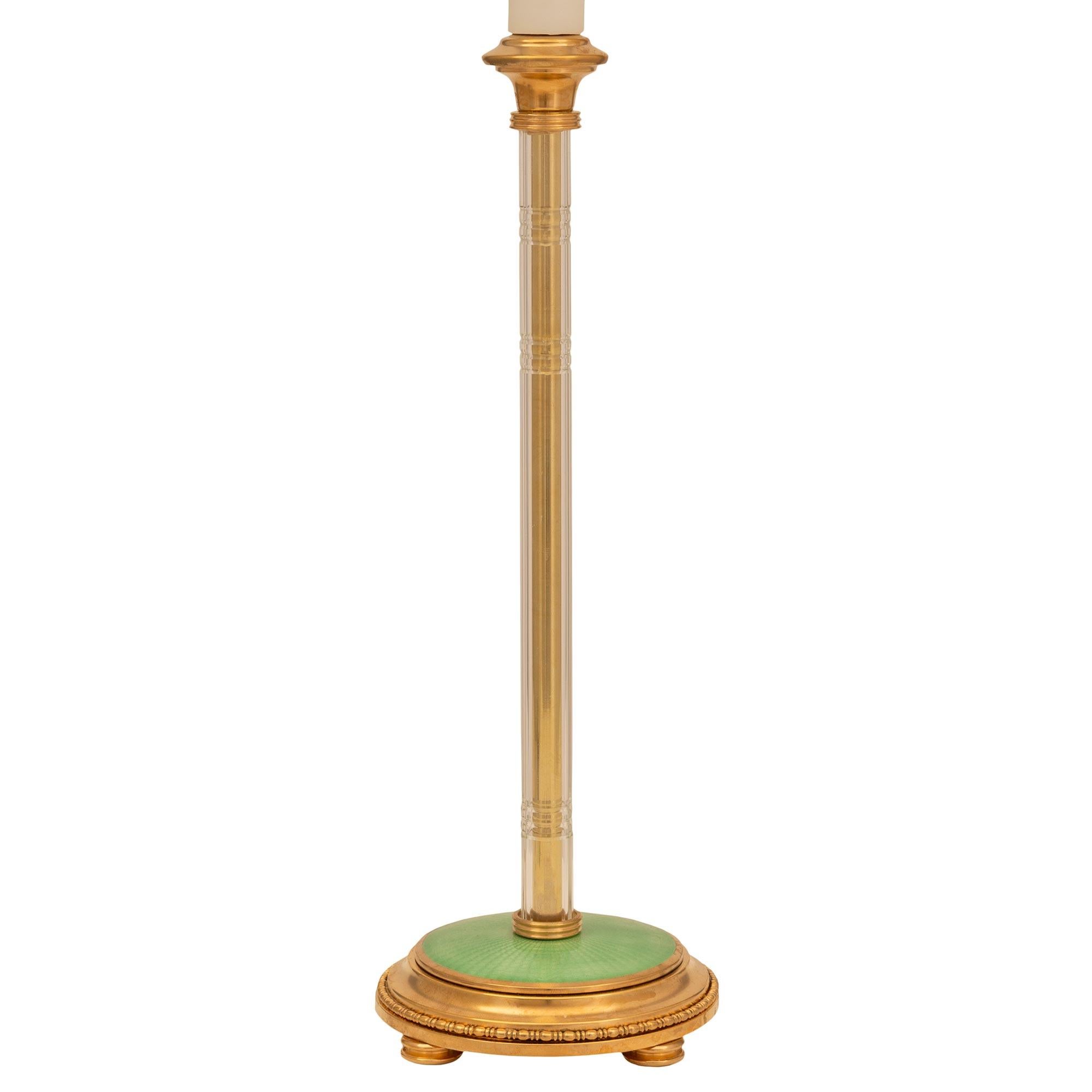 Une paire étonnante de lampes françaises du 19ème siècle, de style Louis XVI, en bronze doré, cristal et émail guilloché. Chaque lampe est surélevée par de fins pieds en forme de chignon tachetés, sous la base circulaire décorée d'une belle bande