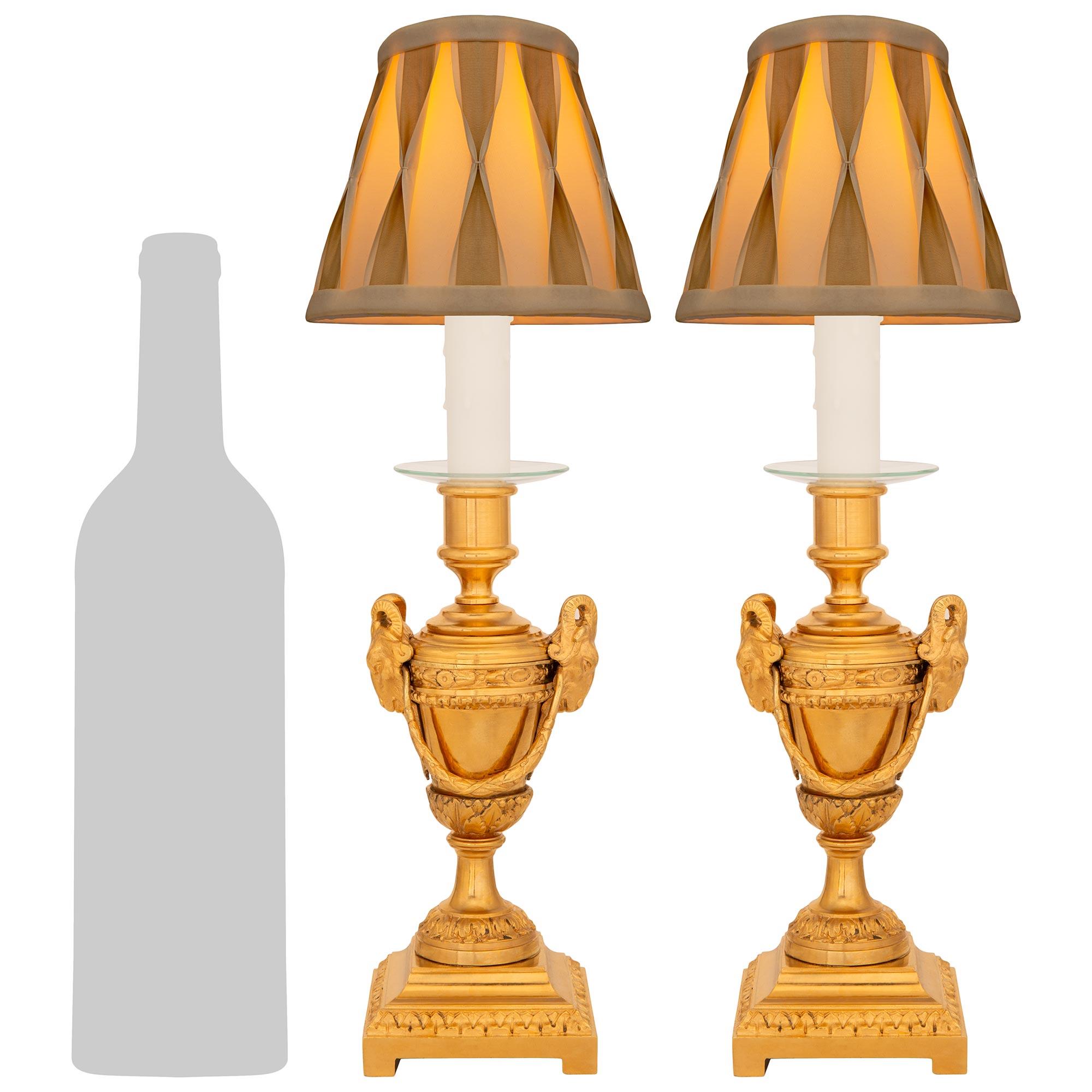 Elegante y muy decorativa pareja de lámparas francesas de Ormolu del siglo XIX, estilo Luis XVI. Cada lámpara candelabro de pequeña escala se eleva sobre un zócalo cuadrado acentuado con una banda foliada. Una banda foliada adicional decora la parte
