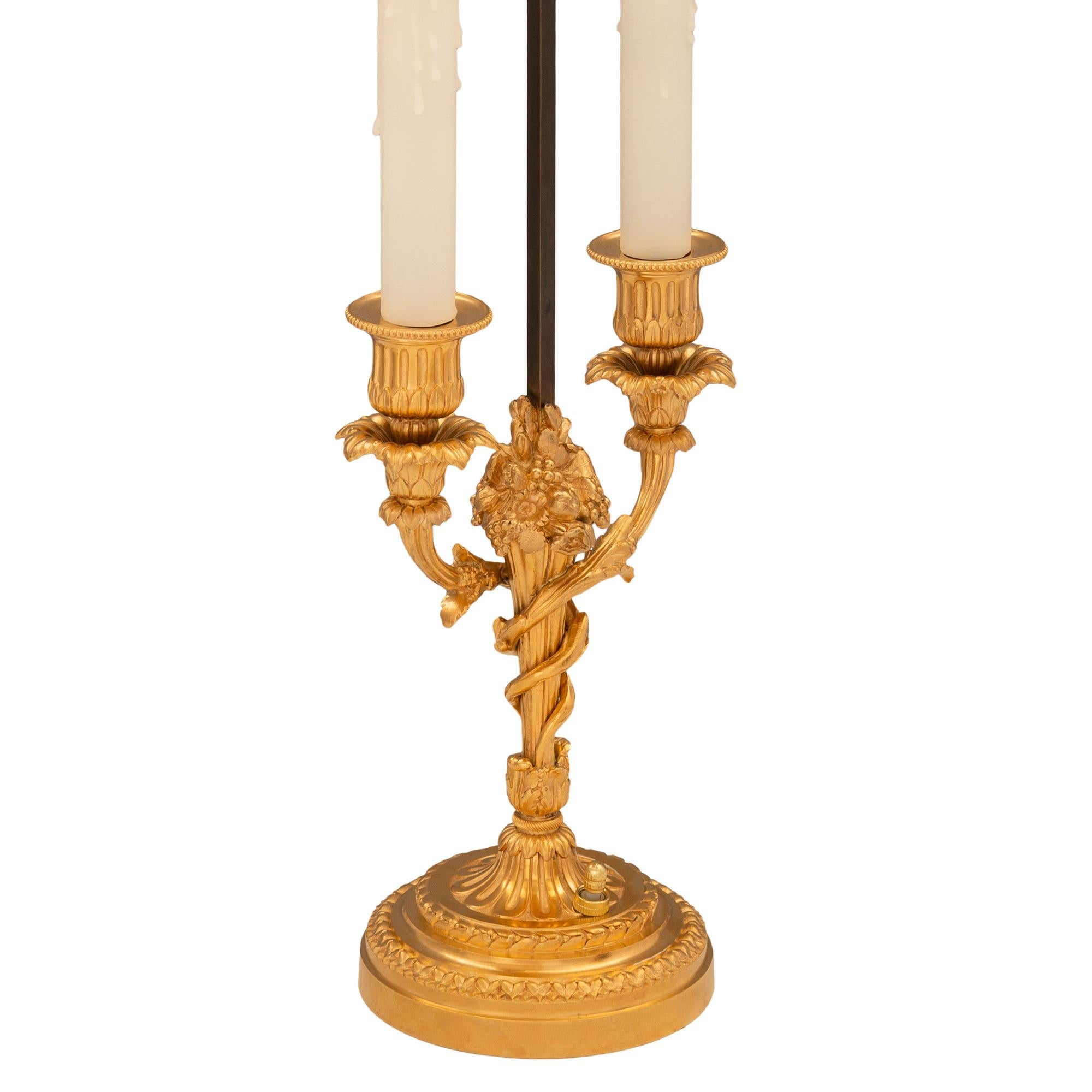 Une paire de lampes en bronze doré de style Louis XVI du 19ème siècle signée Vian. Chaque lampe à deux bras est surélevée par une base circulaire au design finement marbré et décoré de magnifiques bandes feuillues. Les supports centraux fuselés et