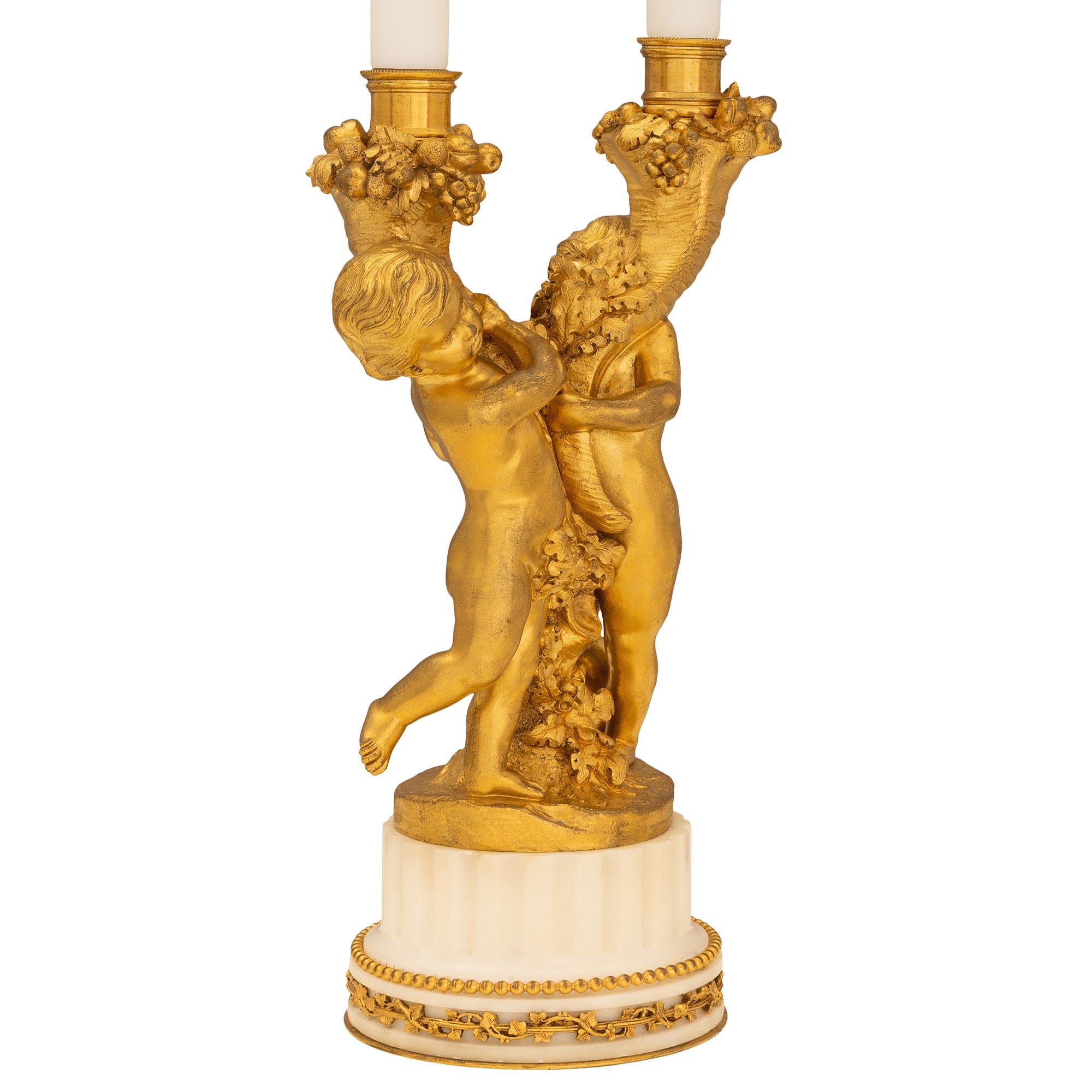 Une très belle paire de lampes candélabres françaises du 19ème siècle, de style Louis XVI, en bronze doré et en marbre blanc de Carrare. Chaque lampe repose sur une base circulaire cannelée décorée d'une guirlande feuillagée en bronze doré et d'une