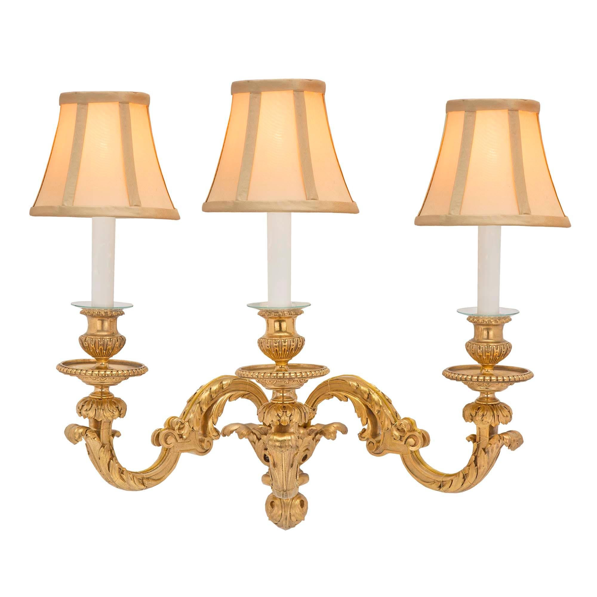 A striking pair of French 19th century Louis XVI st. ormolu sconces. Each three arm sconce is centered by a Fine foliate bottom finial amidst acanthus leaves. The elegantly S scrolled arms are adorned with large richly detailed acanthus leaves. The
