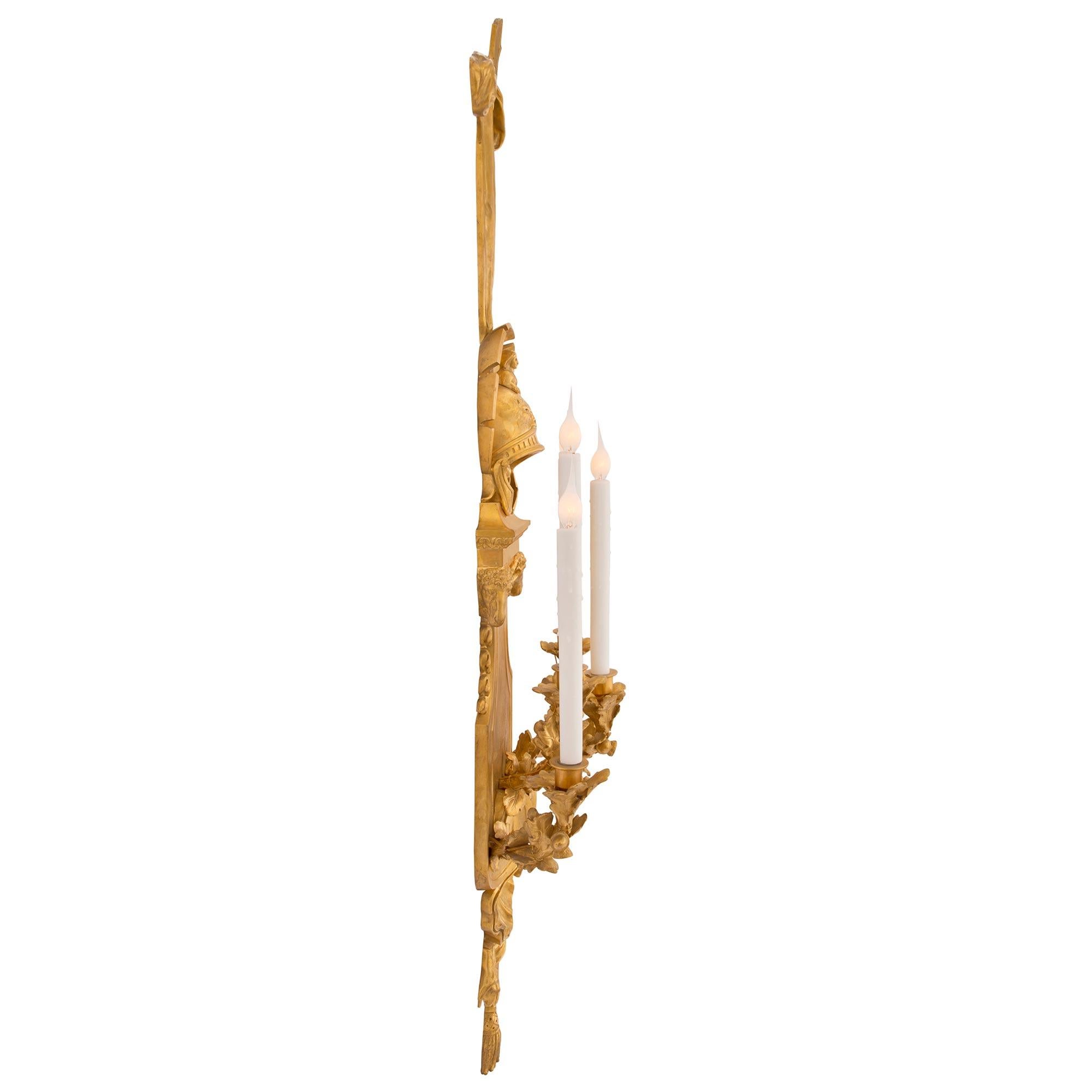 A stunning and most impressive pair of French 19th century Louis XVI st. ormolu sconces. Each large scale five arm sconce is centered by charming tassels at the base below protruding sticks and a striking seashell reserve in a superb satin and