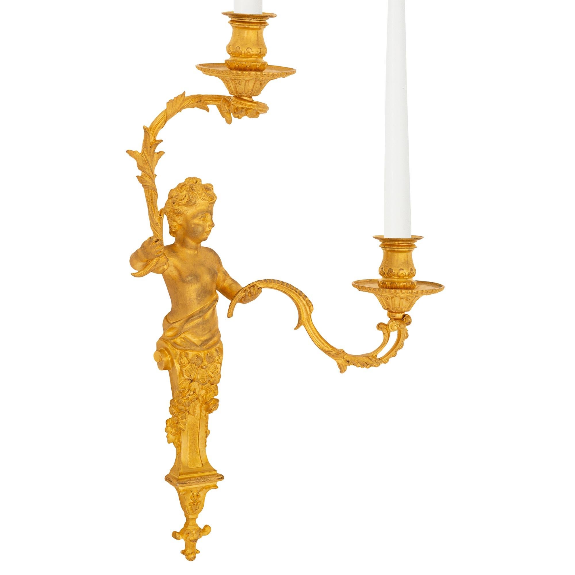 Ein exquisites Paar französischer Ormolu-Leuchter im Stil Louis XVI des 19. Jede zweiarmige Leuchte wird von einem reizvollen, mit Blättern verzierten Endstück unter der hübschen, leicht geschwungenen zentralen Stütze zentriert, die mit kunstvoll