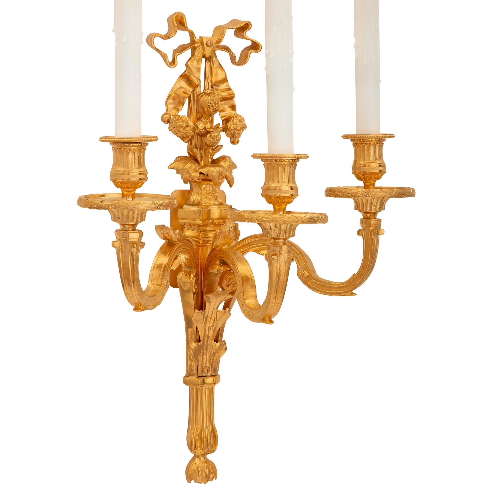Un'attraente coppia di appliques francesi del XIX secolo in stile Luigi XVI ormolu. Ciascuna applique a tre bracci è centrata da un'elegante piastra posteriore affusolata con un raffinato finale inferiore foliato e suggestive foglie d'acanto. I tre