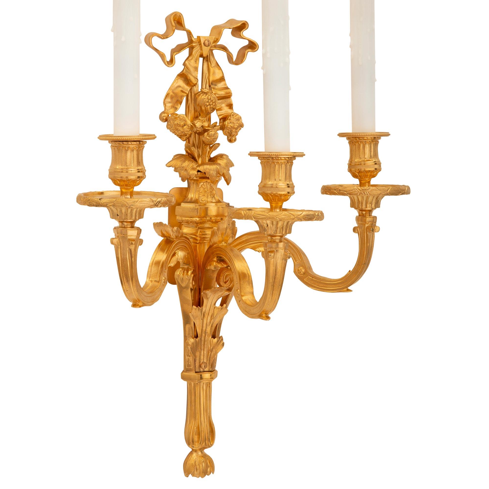 A most attractive pair of French 19th century Louis XVI st. ormolu sconces. Each three arm sconce is centered by an elegant tapered backplate with a fine bottom foliate finial and striking acanthus leaves. The three elegantly scrolled arms are