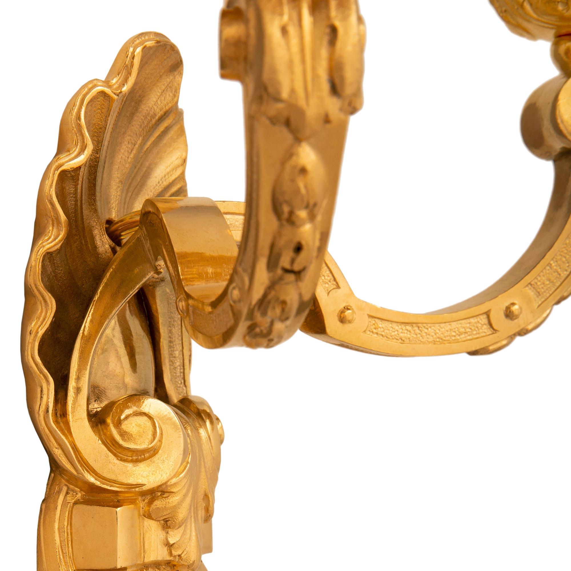 A beautiful pair of French 19th century Louis XVI st. Ormolu sconces. Each two arm sconce in centered by berried acanthus leaves leading up to additional scrolling movements below a stunning seashell reserve. The 'C' scrolled arms are decorated with