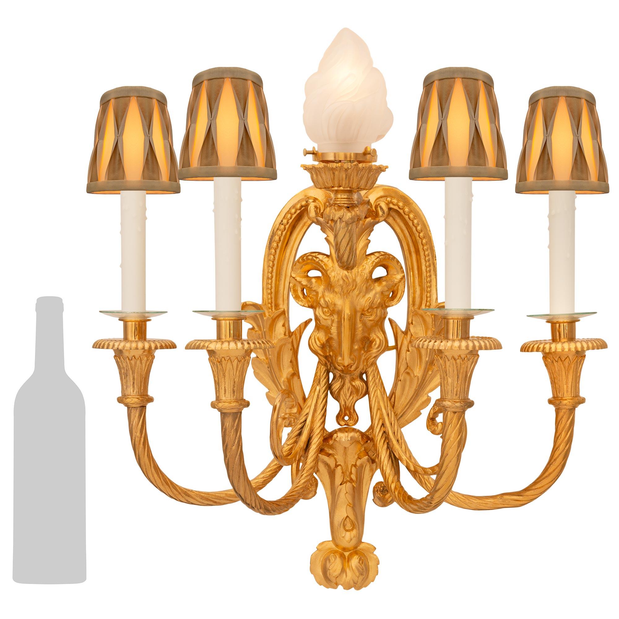 Una splendida e decoratissima coppia di appliques francesi del XIX secolo in stile Luigi XVI in Ormolu. Ogni imponente applique a cinque luci è centrata da un grazioso terminale inferiore decorato con foglie d'acanto. Sopra il terminale si trova la