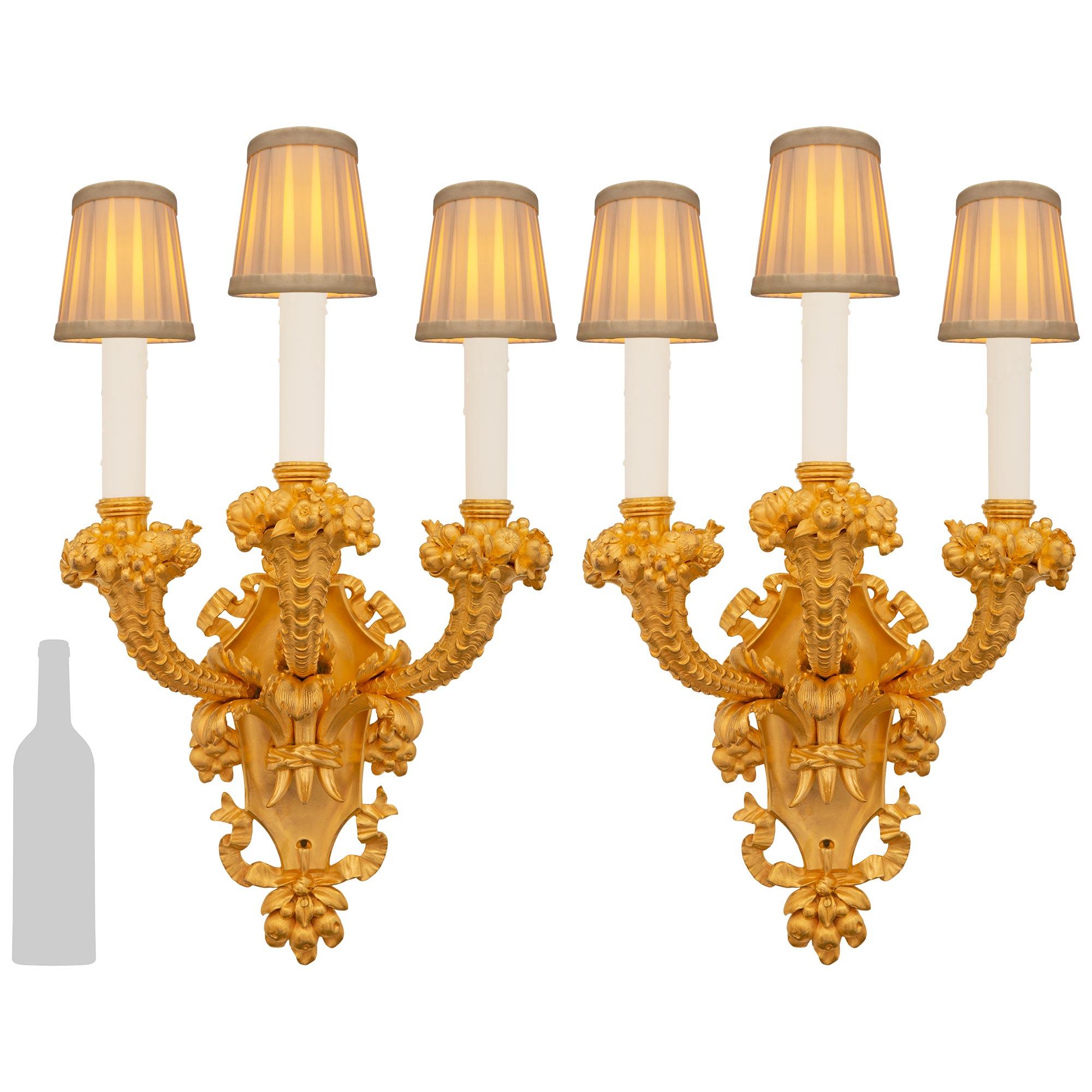 An elegant and high quality pair of French 19th century Louis XVI st. Ormolu sconces, stamped E.F. Caldwell & Co. Each exquisite three arm sconce is centered by a lovely bottom foliate finial tied with a flowing ribbon below the crest shaped back
