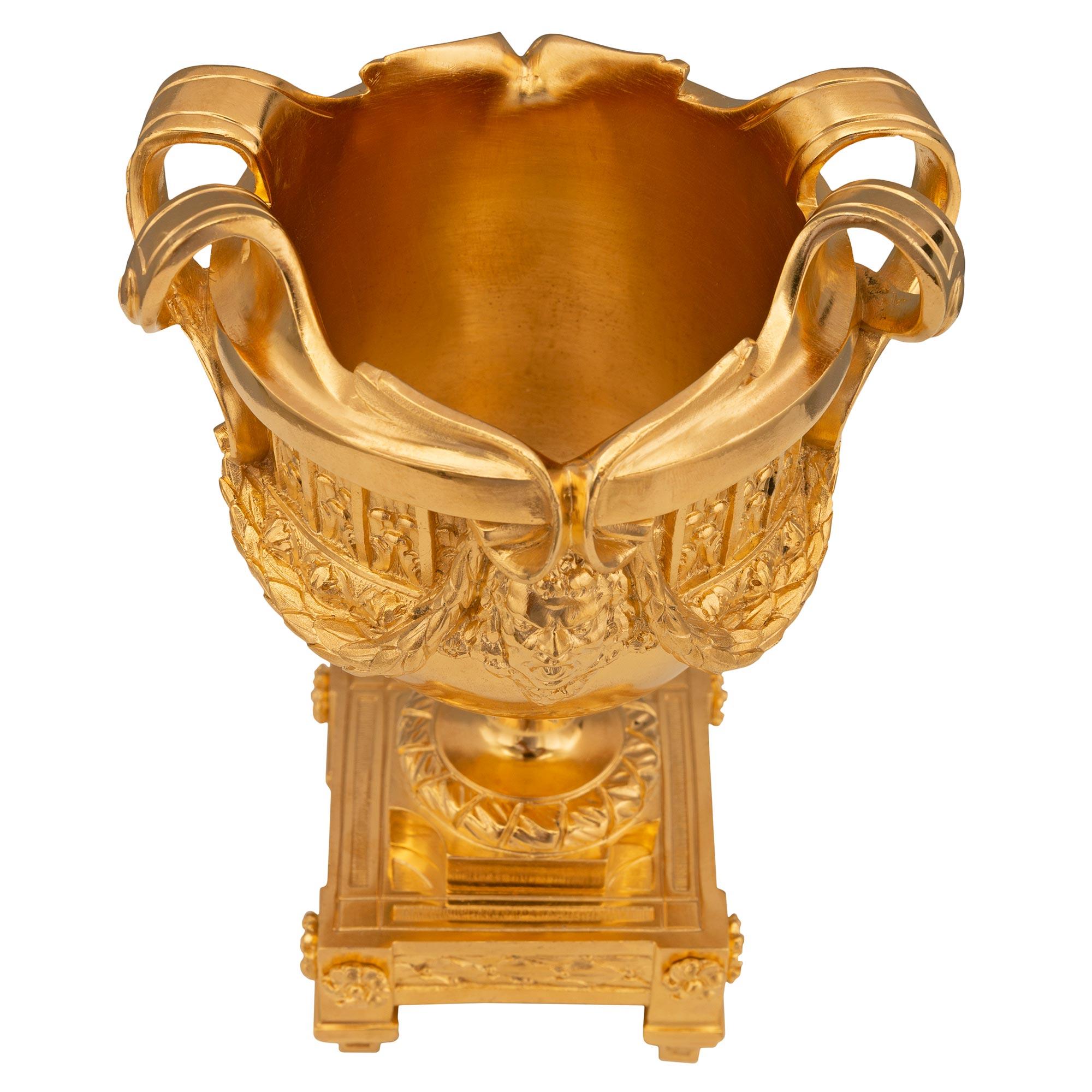 Une belle paire de vases français du 19ème siècle en st. Louis XVI et en bronze doré. Chaque vase élégant est surélevé par de fins pieds-blocs courbés sous la base rectangulaire avec de charmantes rosettes et des bandes de laurier fleuri ajustées.