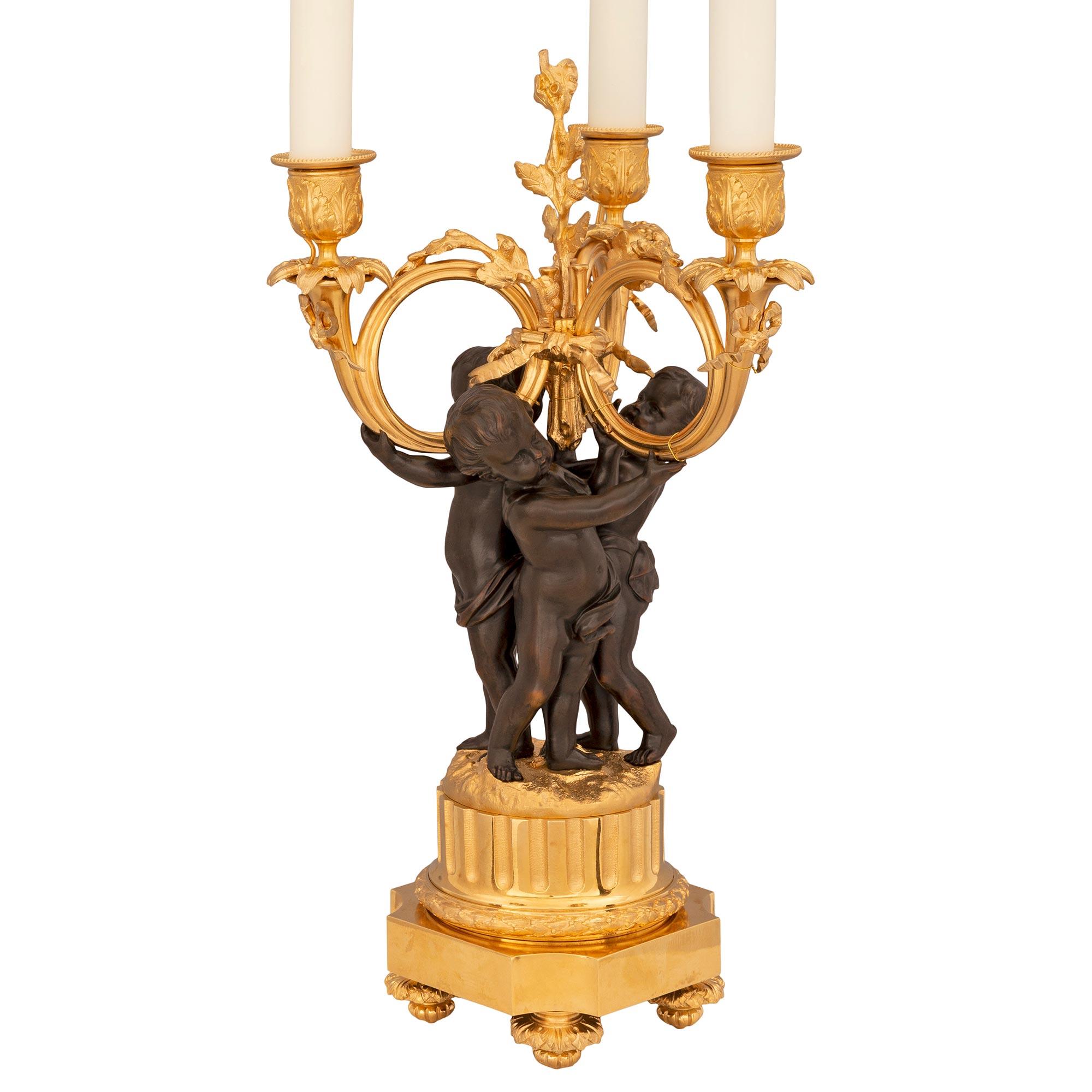 A striking and very high quality pair of French 19th century Louis XVI st. Belle Époque period patinated bronze and ormolu lamps. Each three arm lamp is raised by elegant foliate topie shaped feet below the square base with concave corners and