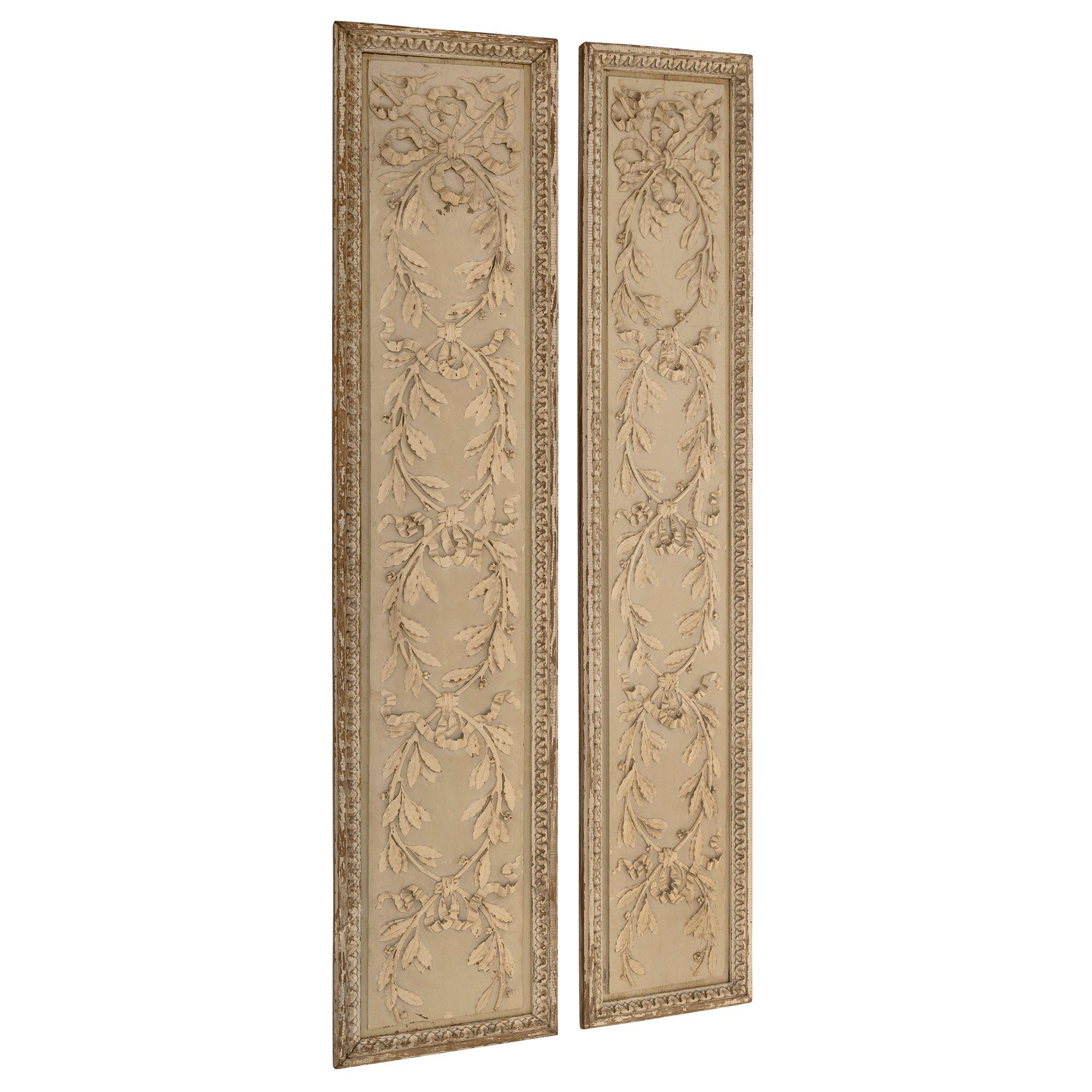 A striking pair of French 19th century Louis XVI st. patinated wall decor panels. Each panel displays beautiful finely detailed intertwining berried laurel branches tied with charming tied ribbons and bows with a most decorative mottled foliate wrap