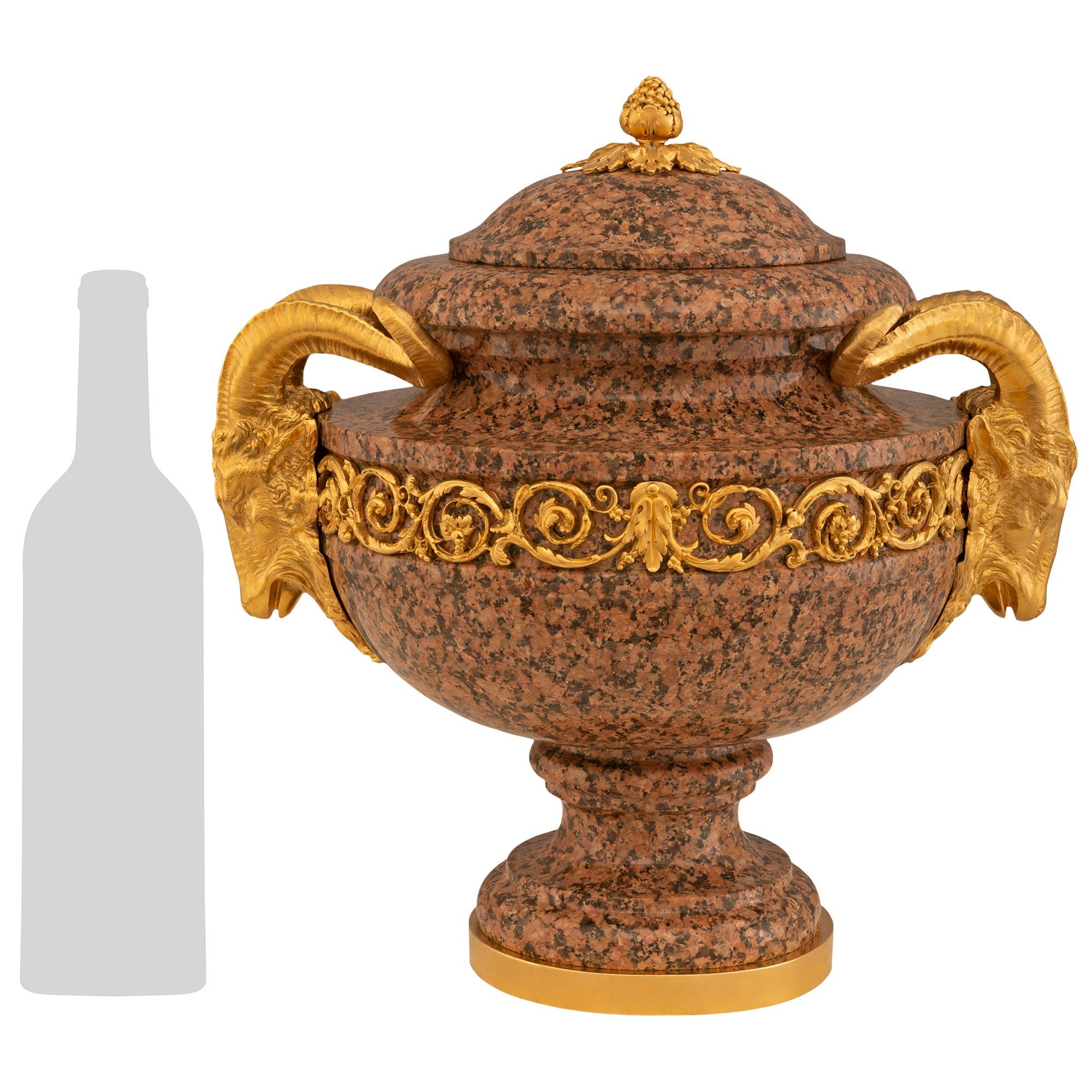 Une paire impressionnante et extrêmement décorative d'urnes à couvercle en granit rose et bronze doré de style Louis XVI du XIXe siècle. La paire repose sur des bases circulaires en bronze doré sous le socle en granit tacheté. L'urne est surmontée
