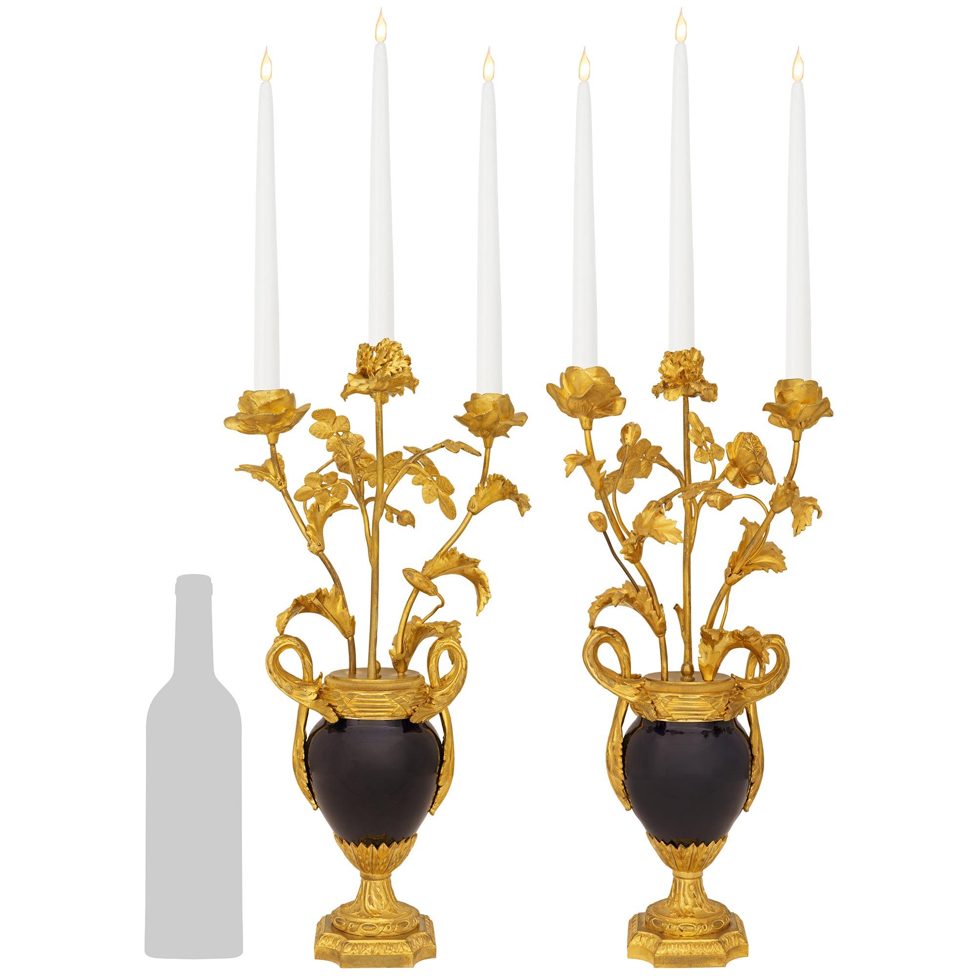 A stunning and most elegant pair of French 19th century Louis XVI st. Sèvres Porcelain and Ormolu candelabras. Each wonderful three arm cobalt blue Porcelain candelabra is raised by a mottled square Ormolu base with concave corners and a fine Rais