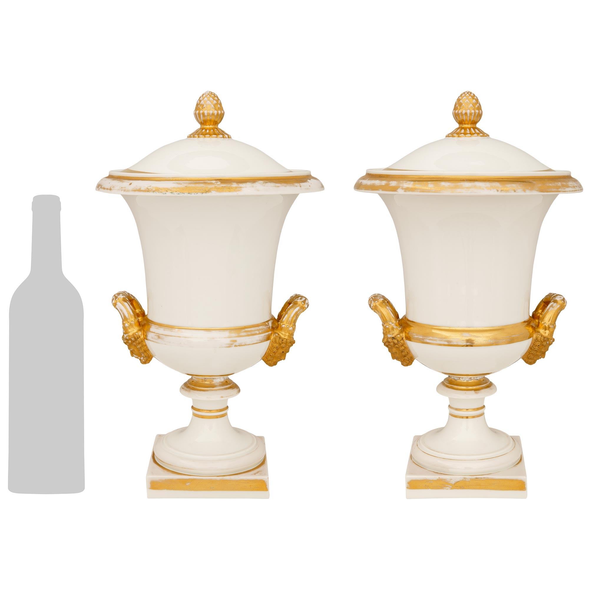 Elegante pareja de cubiteras/urnas de vino francesas del siglo XIX, de estilo Luis XVI, de Porcelaine de Paris y dorado. Cada maravilloso rafraichissoir se eleva sobre una base cuadrada de porcelana con bandas doradas bajo un elegante zócalo que