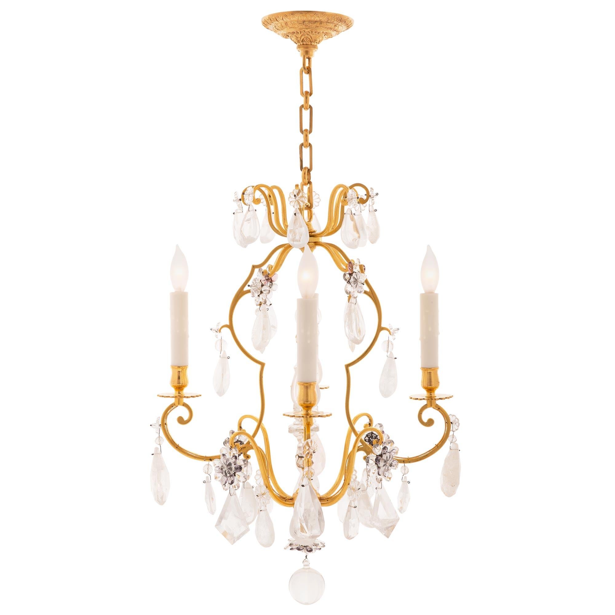 A charming and most decorative pair of French early 19th century Louis XVI st. ormolu, rock crystal, and colored glass chandeliers. Each four arm chandelier is centered by a beautiful solid crystal ball with charming floral crystals and amethyst