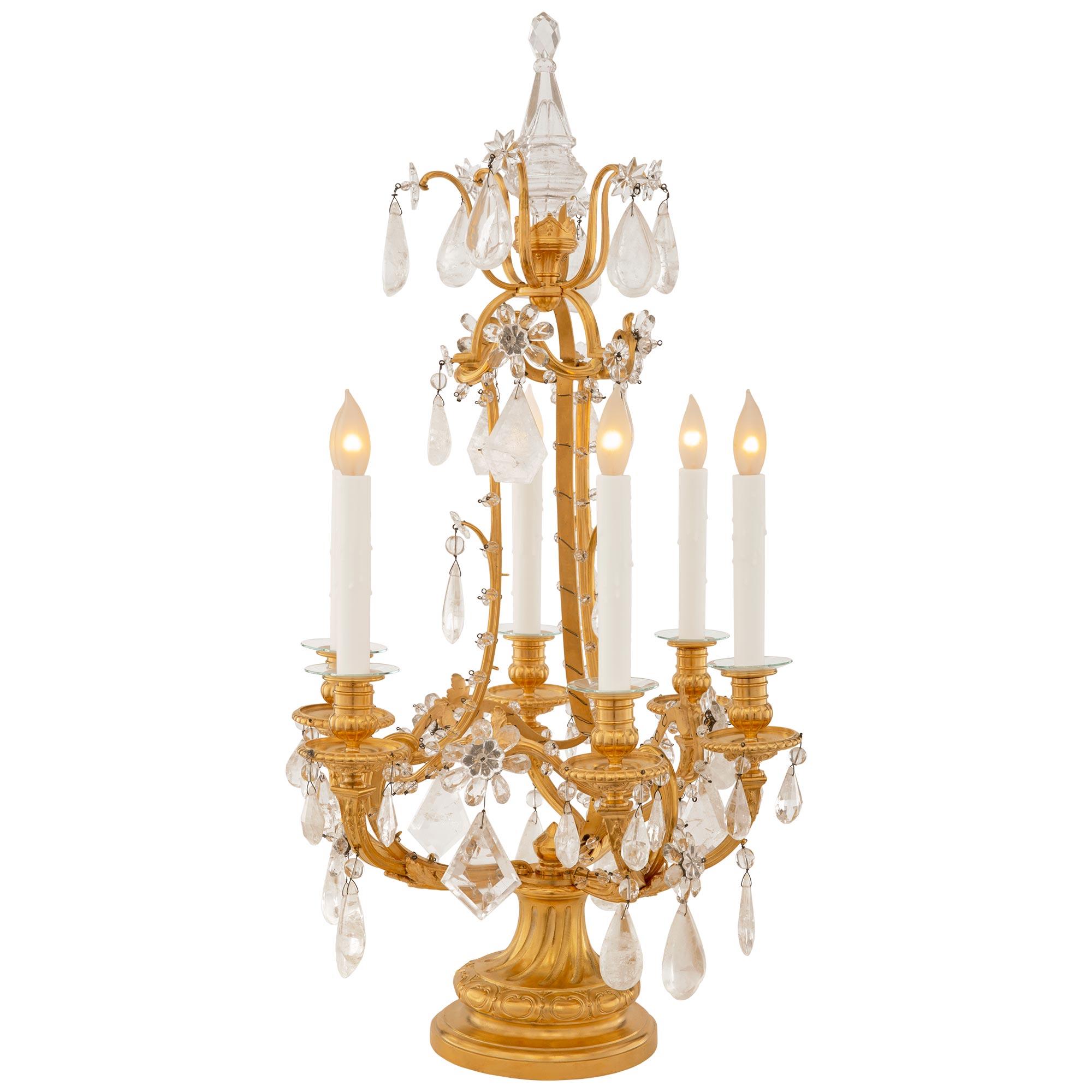 A stunning and highly quality pair of French 19th century Louis XVI st. Rock Crystal and Crystal Girandole lamps. Each six light Girandole is raised by a circular Ormolu base with a mottled edge below the lightly spiraling fluted socle pedestal with