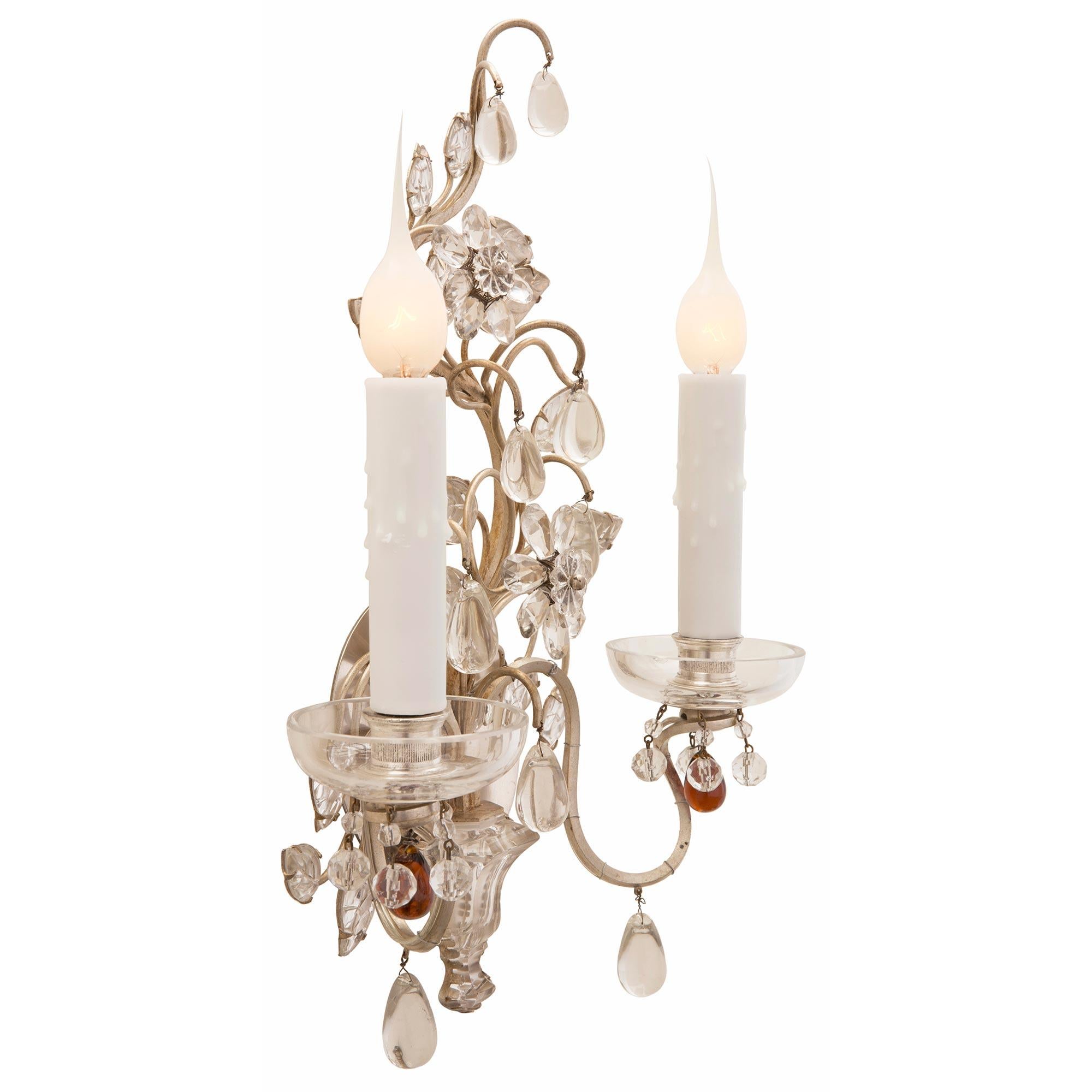 A beautiful and extremely decorative true pair of French 19th century Louis XVI st. silvered bronze, silver leaf, and crystal sconces. Each two arm sconce is centered by a most elegant urn shaped bottom crystal reserve set on a silvered leaf