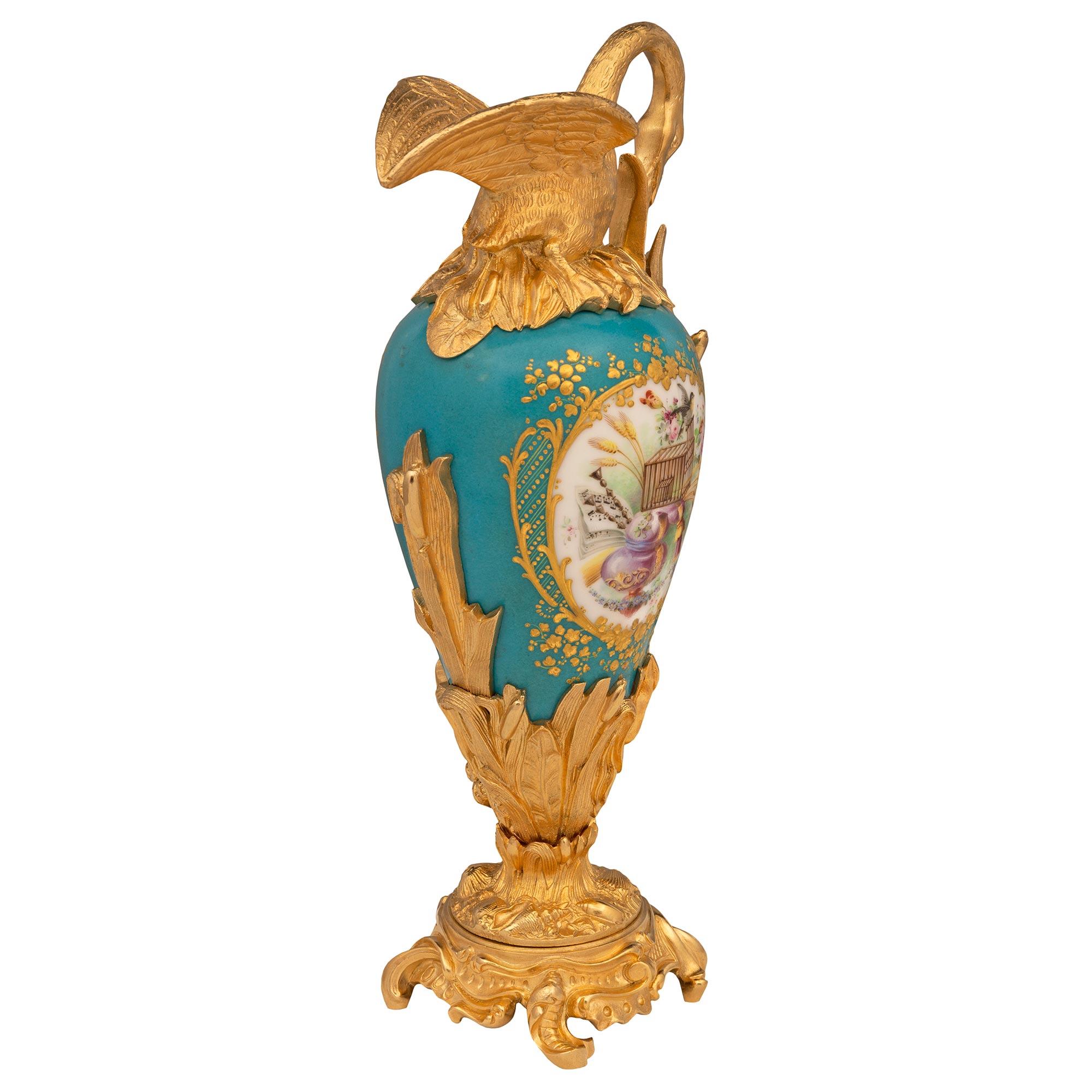 Paire d'élégantes aiguières en porcelaine de Sèvres et bronze doré, de style Louis XVI et d'époque Belle Époque, datant du XIXe siècle. Chaque aiguière est surélevée par une base en bronze doré saisissante, ornée de mouvements feuillagés uniques et
