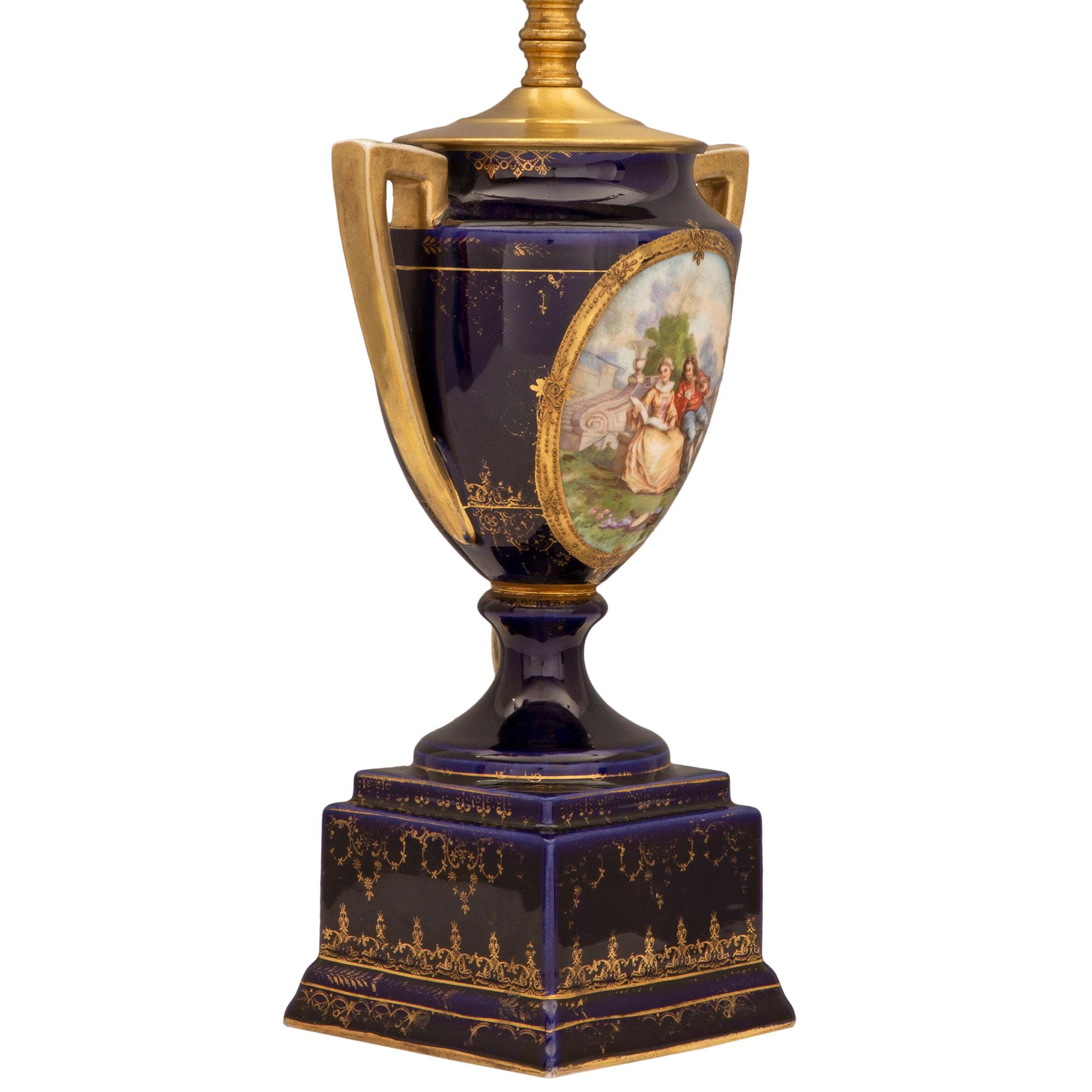 Une élégante paire de lampes en porcelaine de Sèvres de style Louis XVI du XIXe siècle. Chaque lampe est surmontée d'une base carrée mouchetée décorée de fins motifs feuillagés dorés et enroulés. Au-dessus des piédestaux en forme de socle, les corps