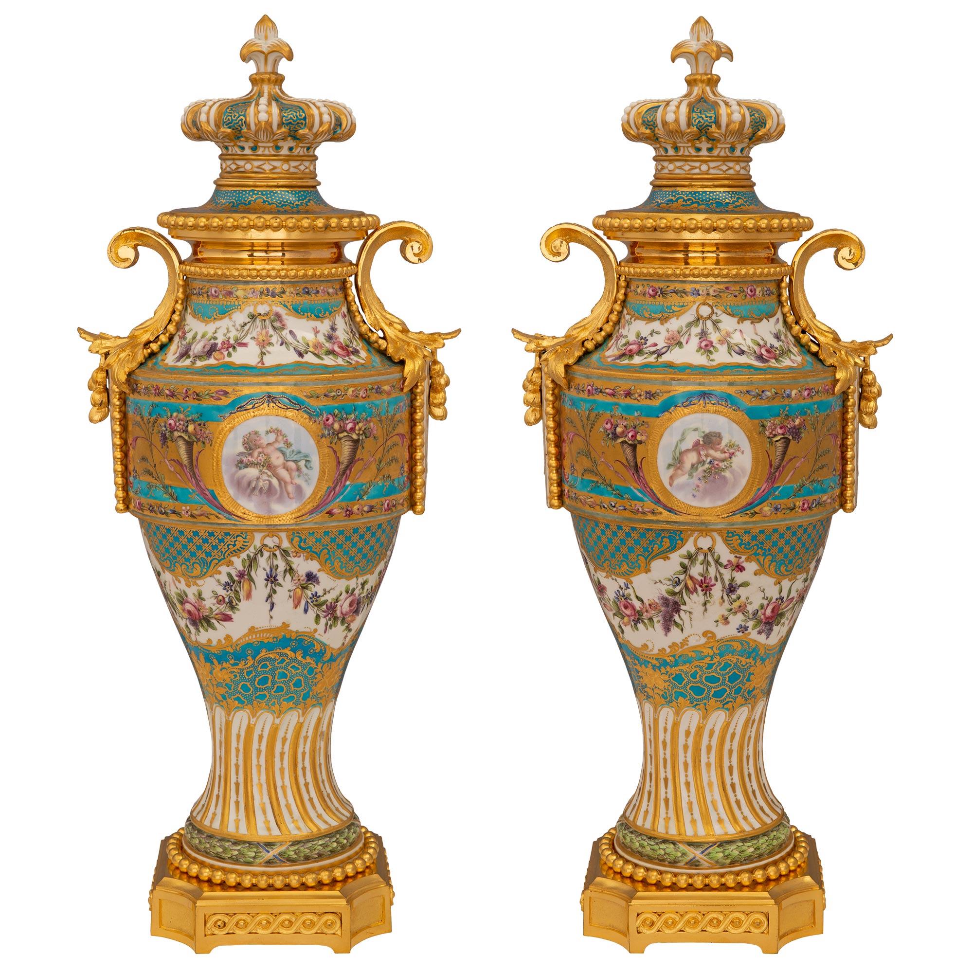 A stunning and extremely decorative true pair of French 19th century Louis XVI st. Sèvres porcelain and ormolu lidded urns. Each urn is raised by a square ormolu base with concave corners, decorated with fitted decorative interlocking designs and a