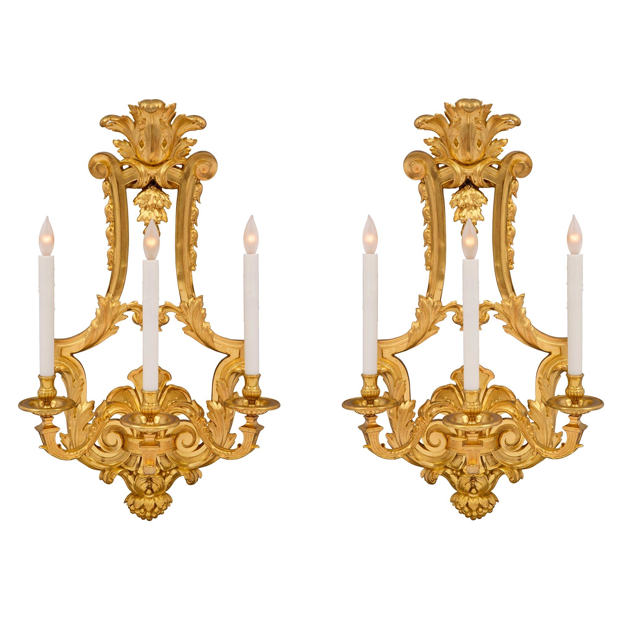 A striking and high quality pair of French 19th century Louis XVI st. three arm ormolu sconces. Each sconce is centered by an impressive berried foliate finial below large richly chased scrolled acanthus leaves. The three elegantly scrolled arms