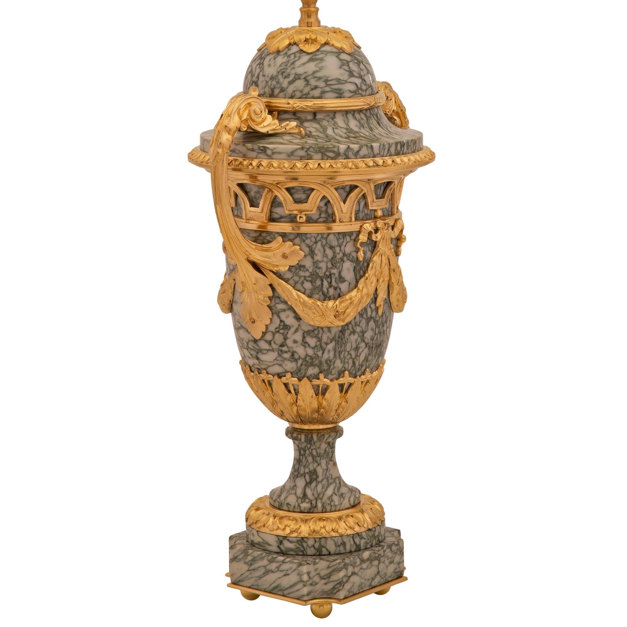 Splendida coppia di lampade francesi del XIX secolo in marmo e ormeggio Vert Campan. Ogni lampada è sollevata da una base quadrata in marmo Vert Campan con eleganti lati concavi e raffinati piedini a sfera in ormù sotto il piedistallo circolare a