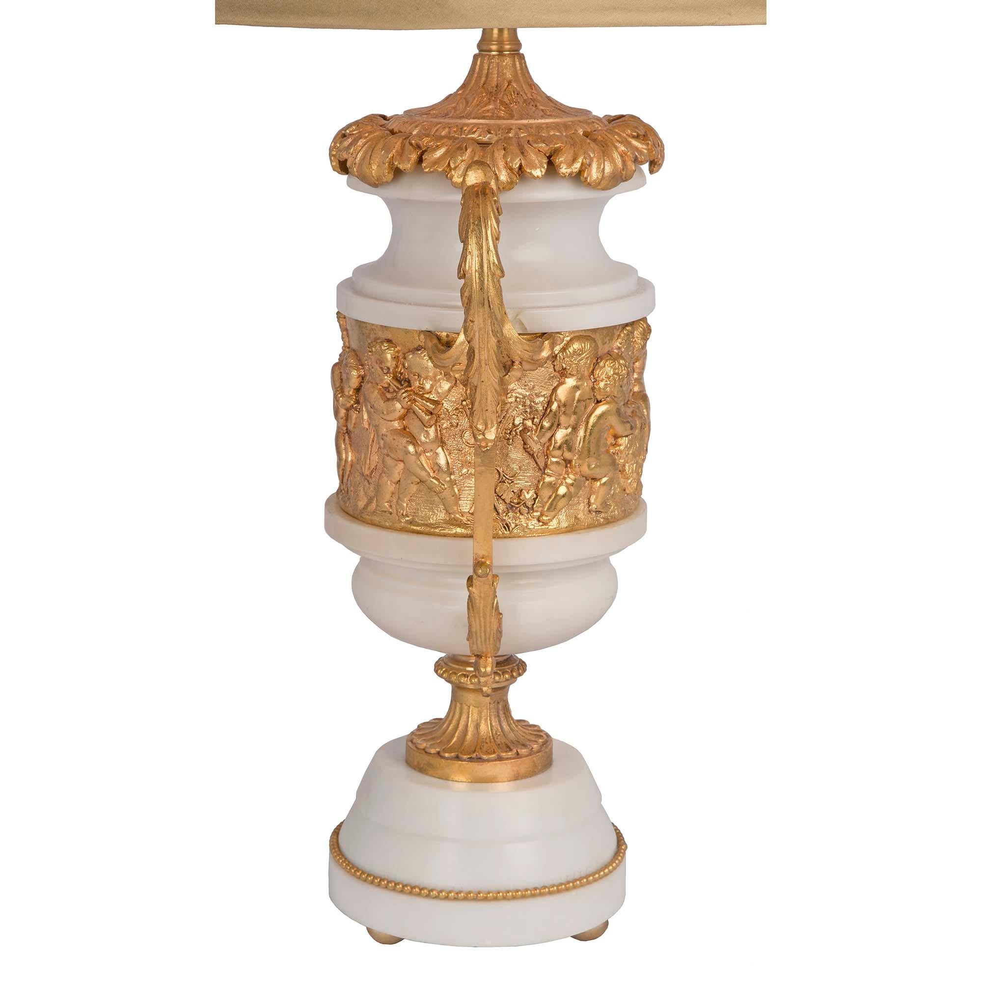 A charming and high quality pair of French 19th century Louis XVI st. white Carrara marble and ormolu lamps. Each lamp is raised by a circular white Carrara marble base with a beaded ormolu trim tapered to the elegant fluted ormolu socle pedestal.