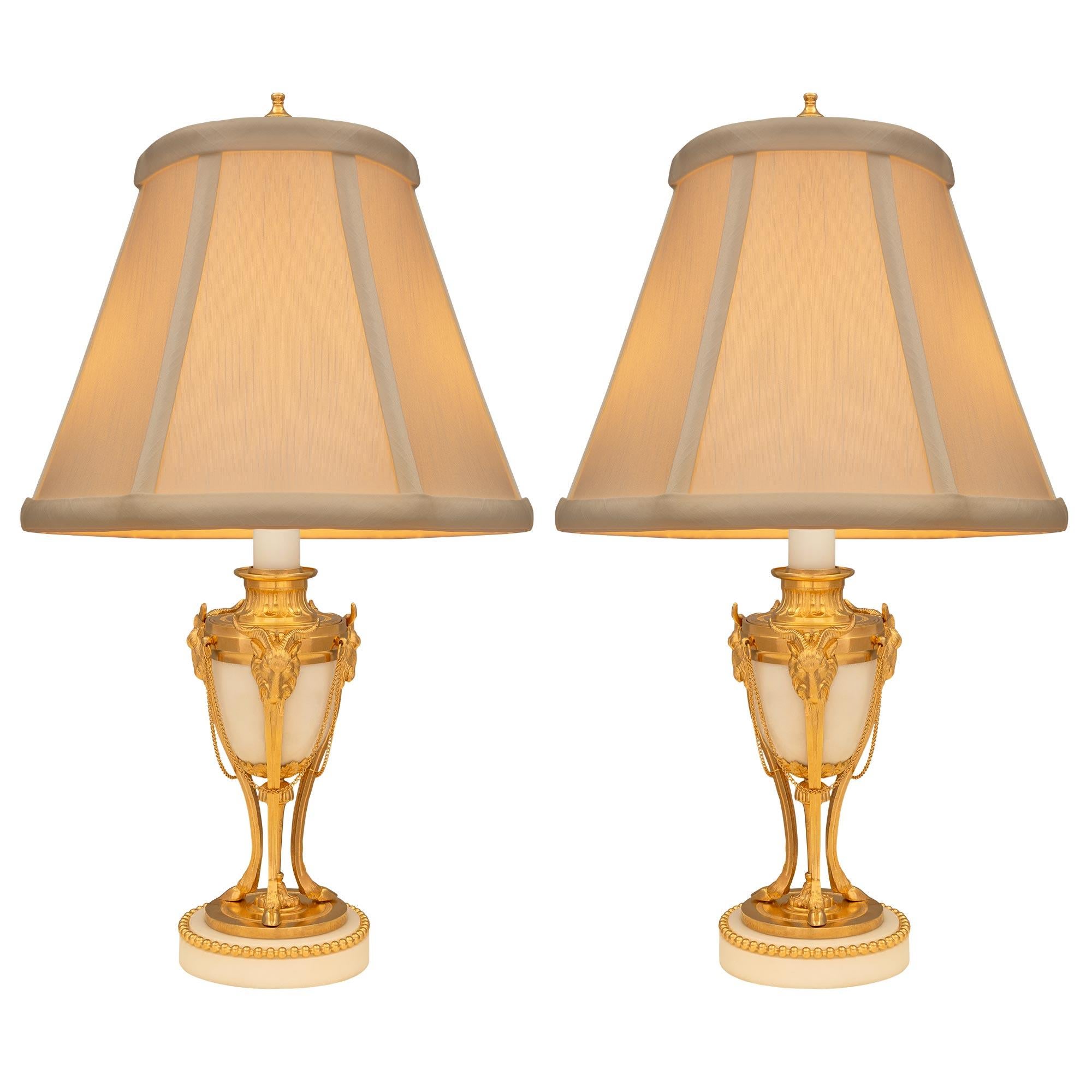 Une élégante paire de lampes françaises du XIXe siècle, de style Louis XVI, en marbre blanc de Carrare et bronze doré. Chaque lampe est surélevée par une base circulaire en marbre blanc de Carrare avec une fine bande perlée en bronze doré. Trois