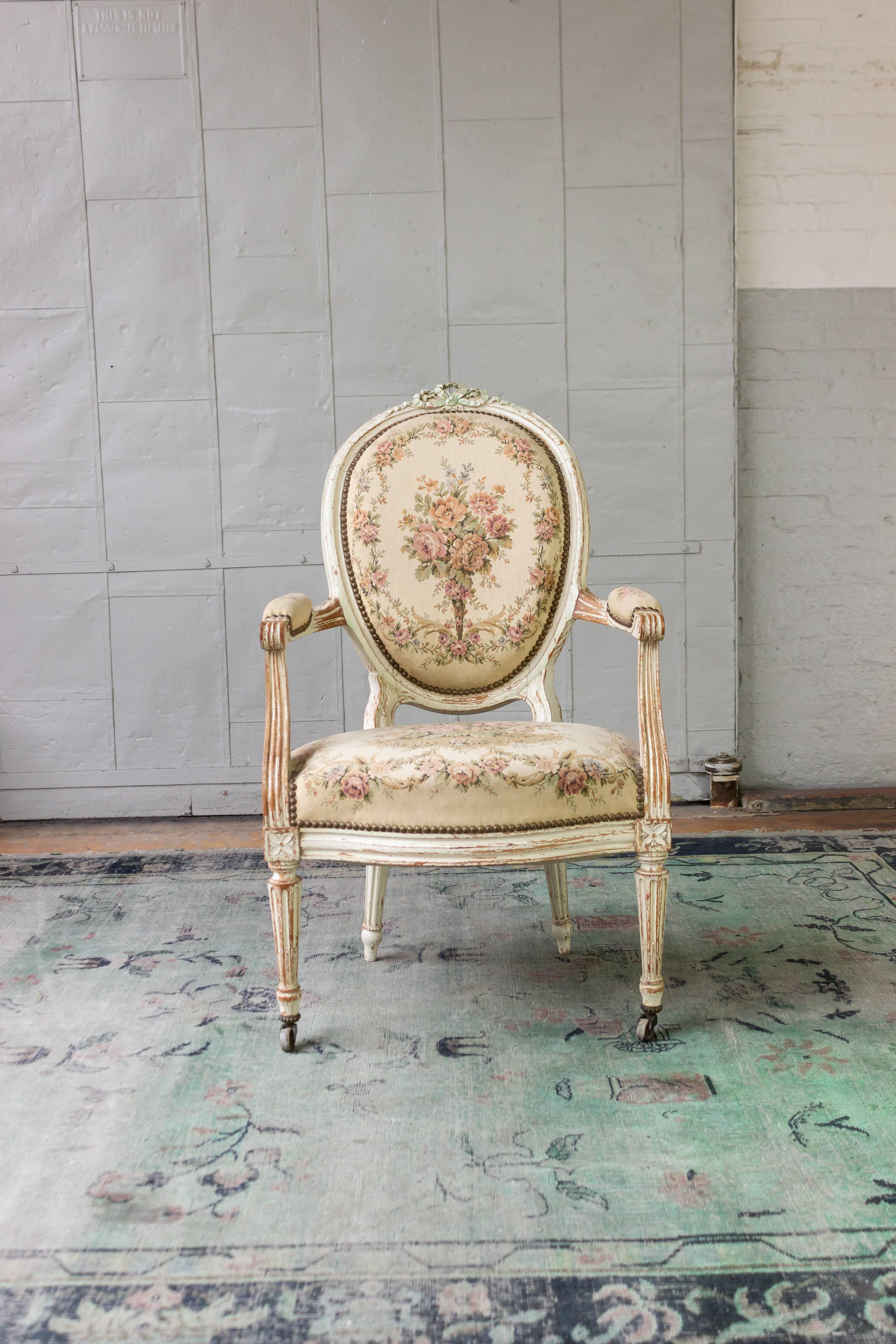 An exquisite pair of French Louis XVI style armchairs. Elevate your décor to the heights of luxury and elegance with this classic pair of 19th century French armchairs. Crafted in white washed, patinated frames rich with intricate carvings and